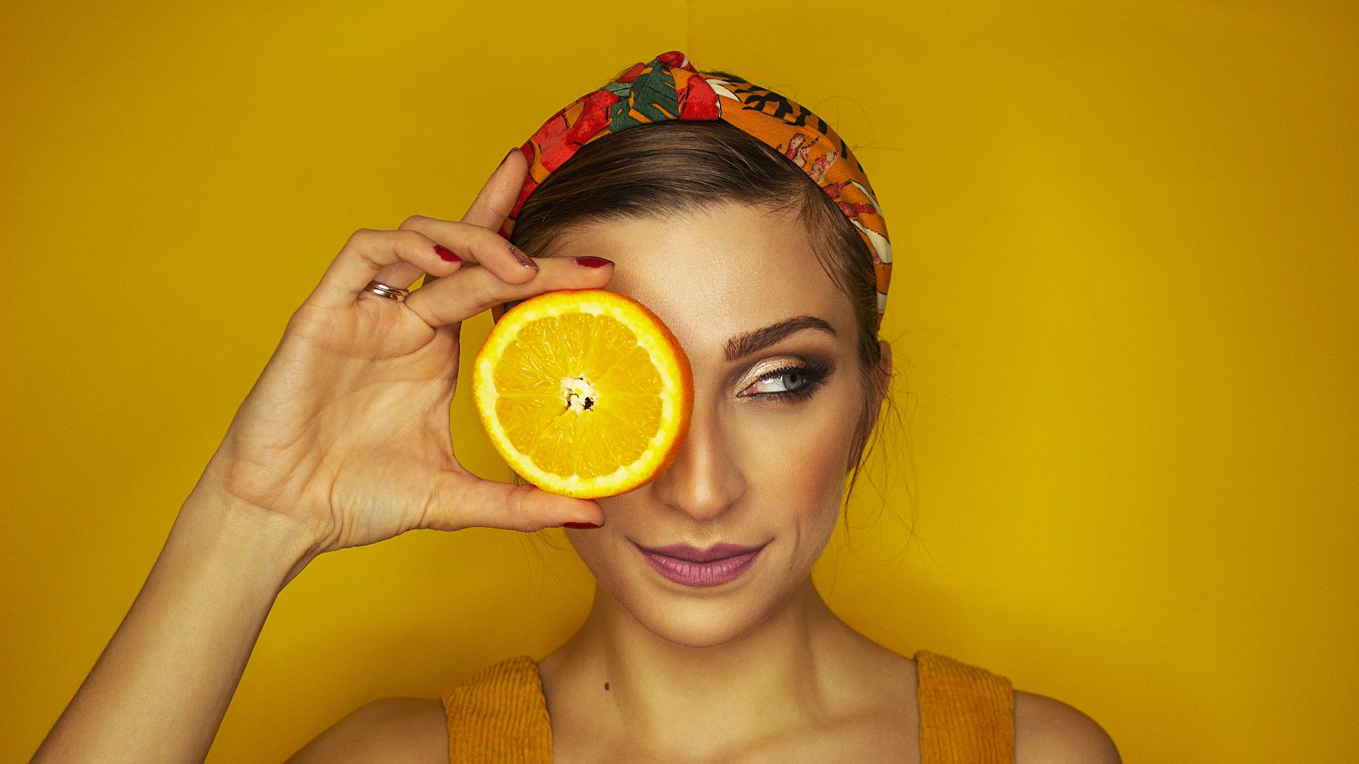woman covering her right eye with orange slice