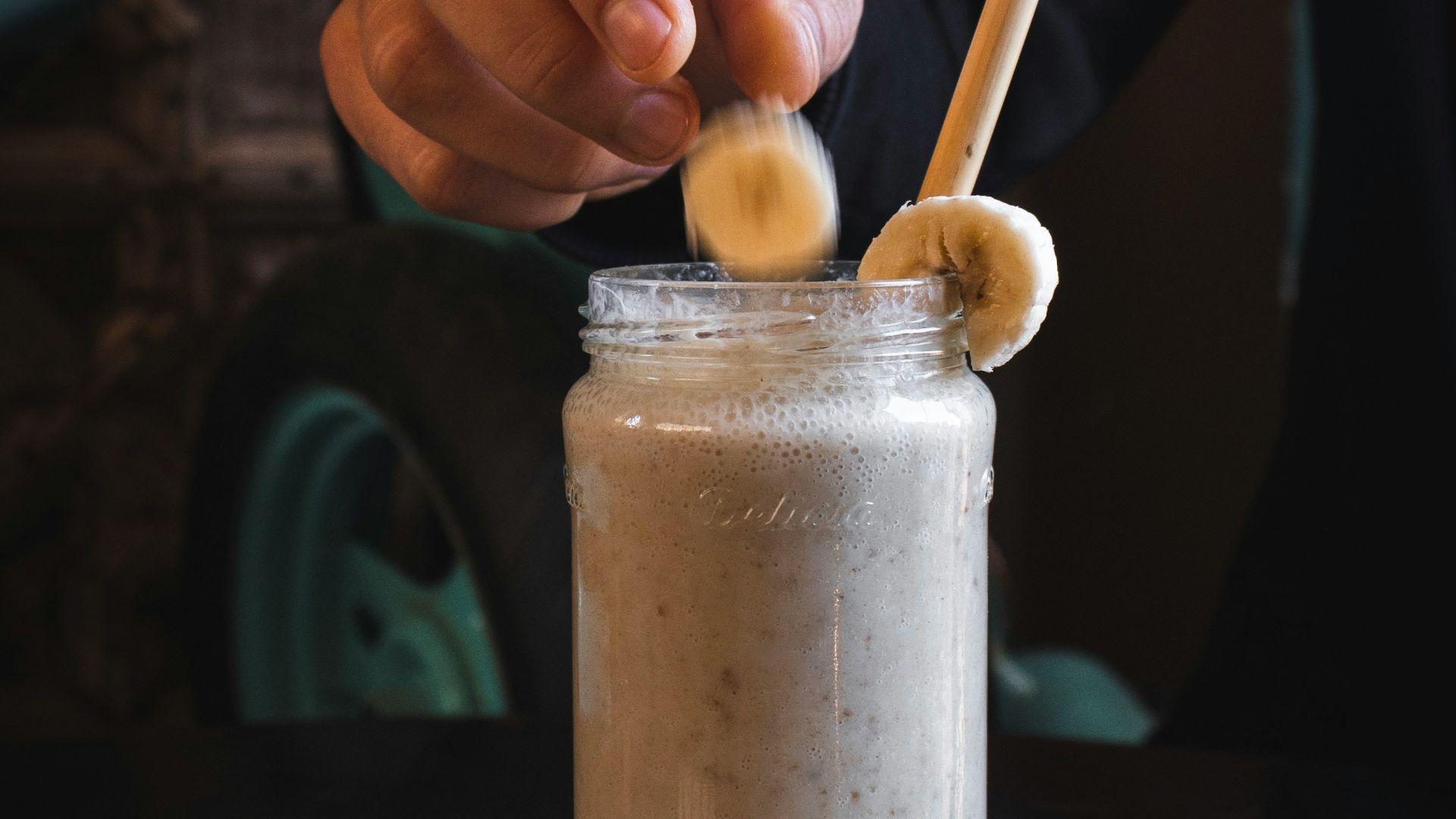 person putting sliced banana fruit on top of jar