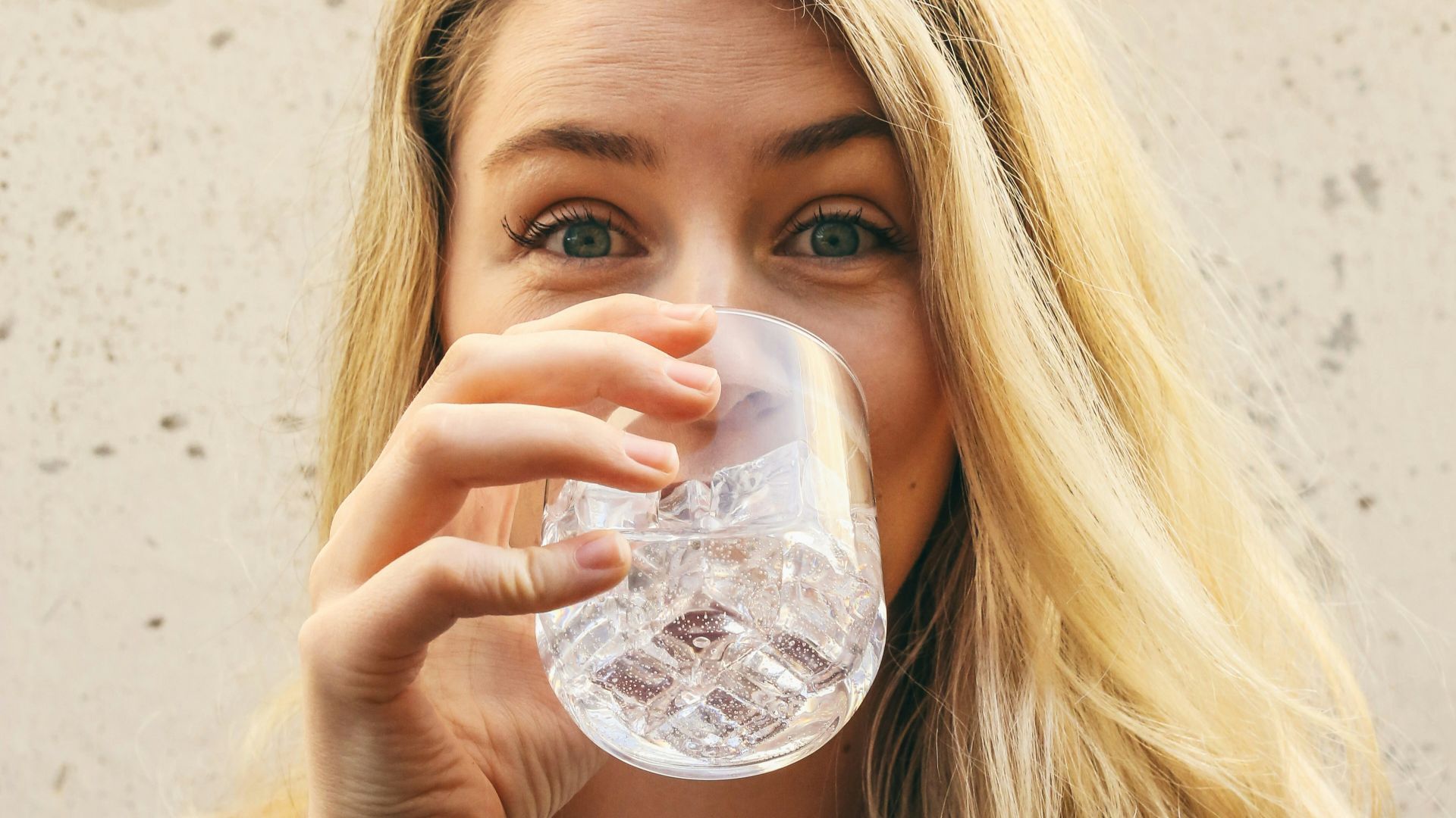 woman in white crew neck shirt drinking water