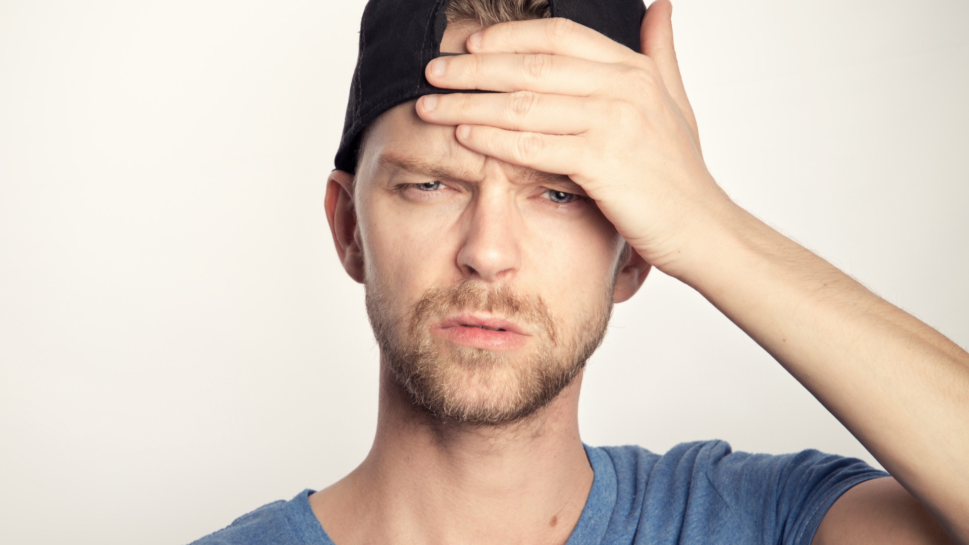 man in blue crew neck shirt covering his face