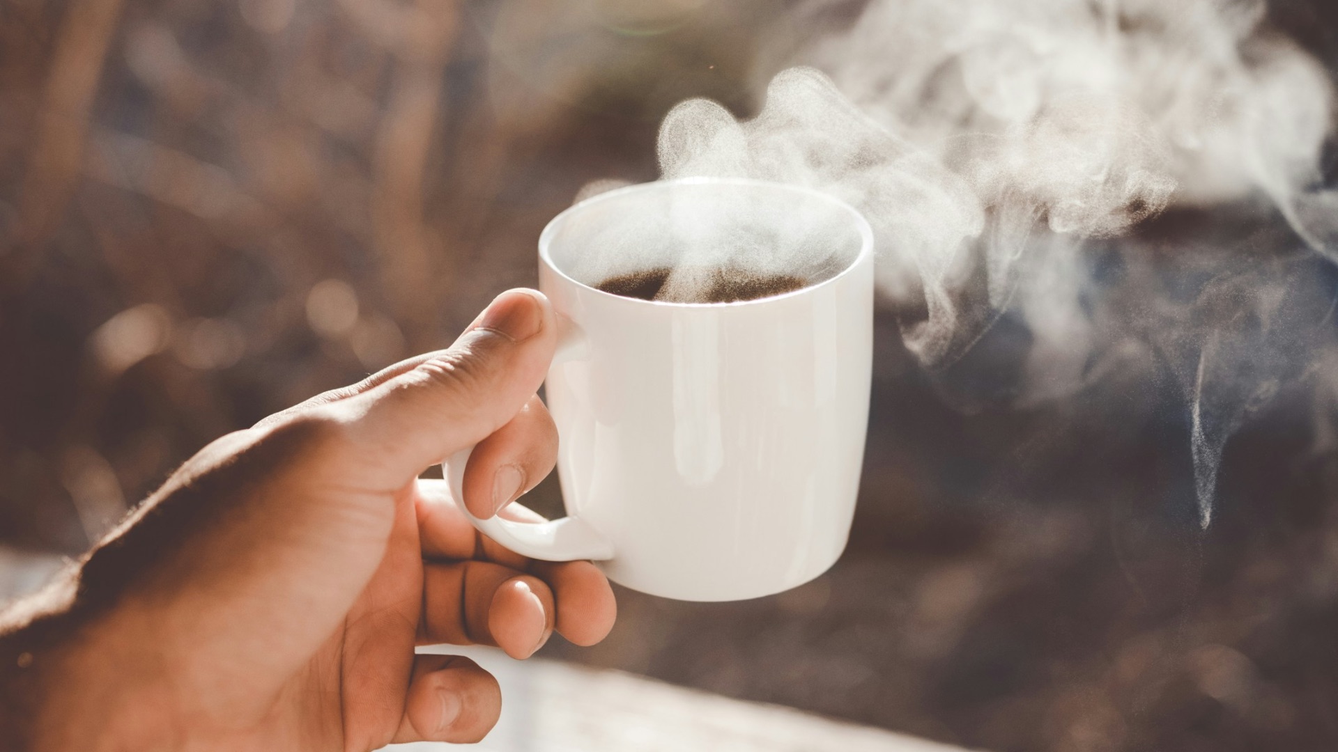 person holding white ceramic cup with hot coffee