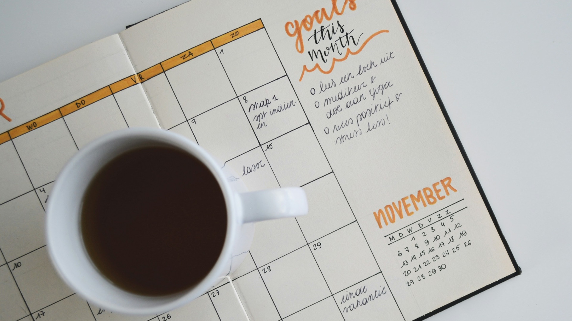 white ceramic mug with coffee on top of a planner