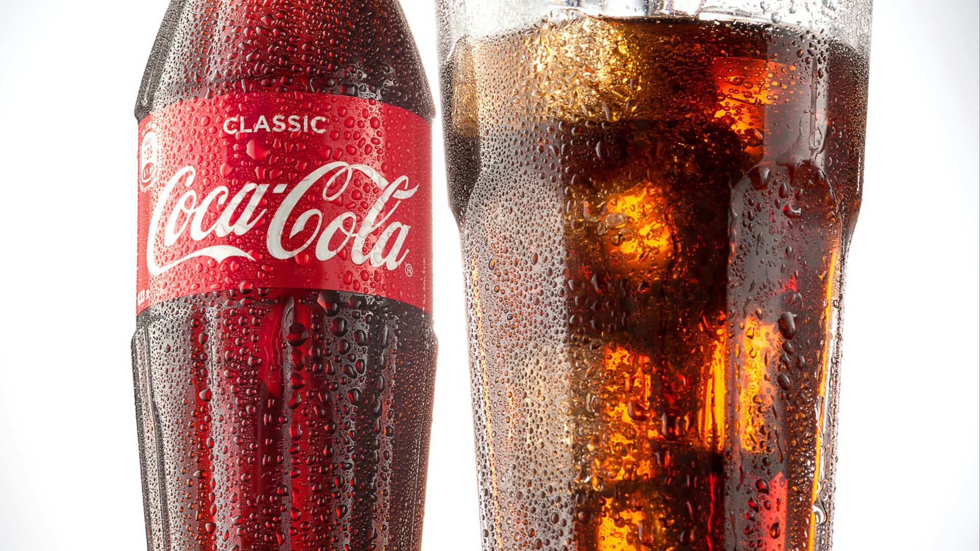 coca cola bottle beside drinking glass