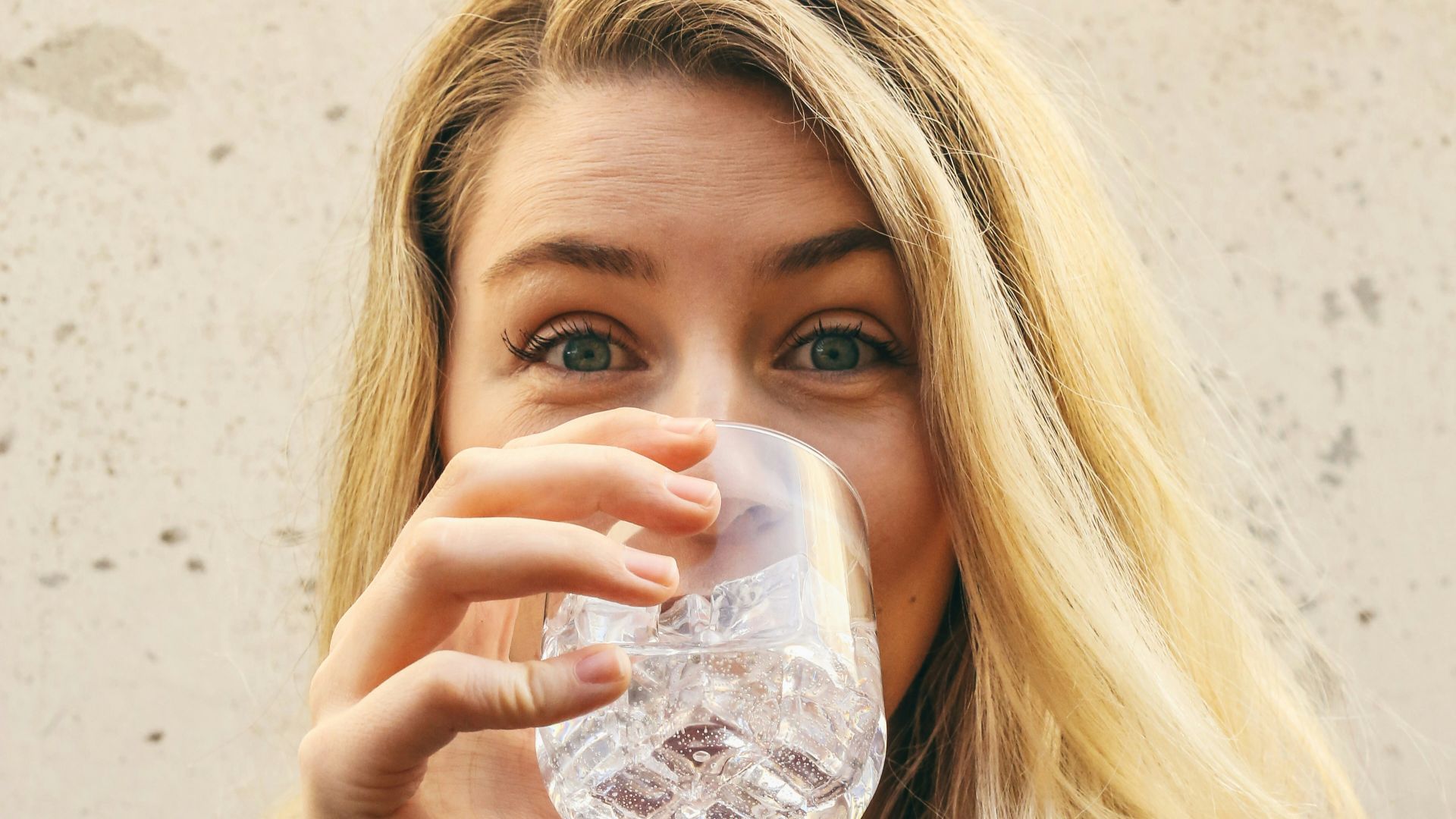 woman in white crew neck shirt drinking water