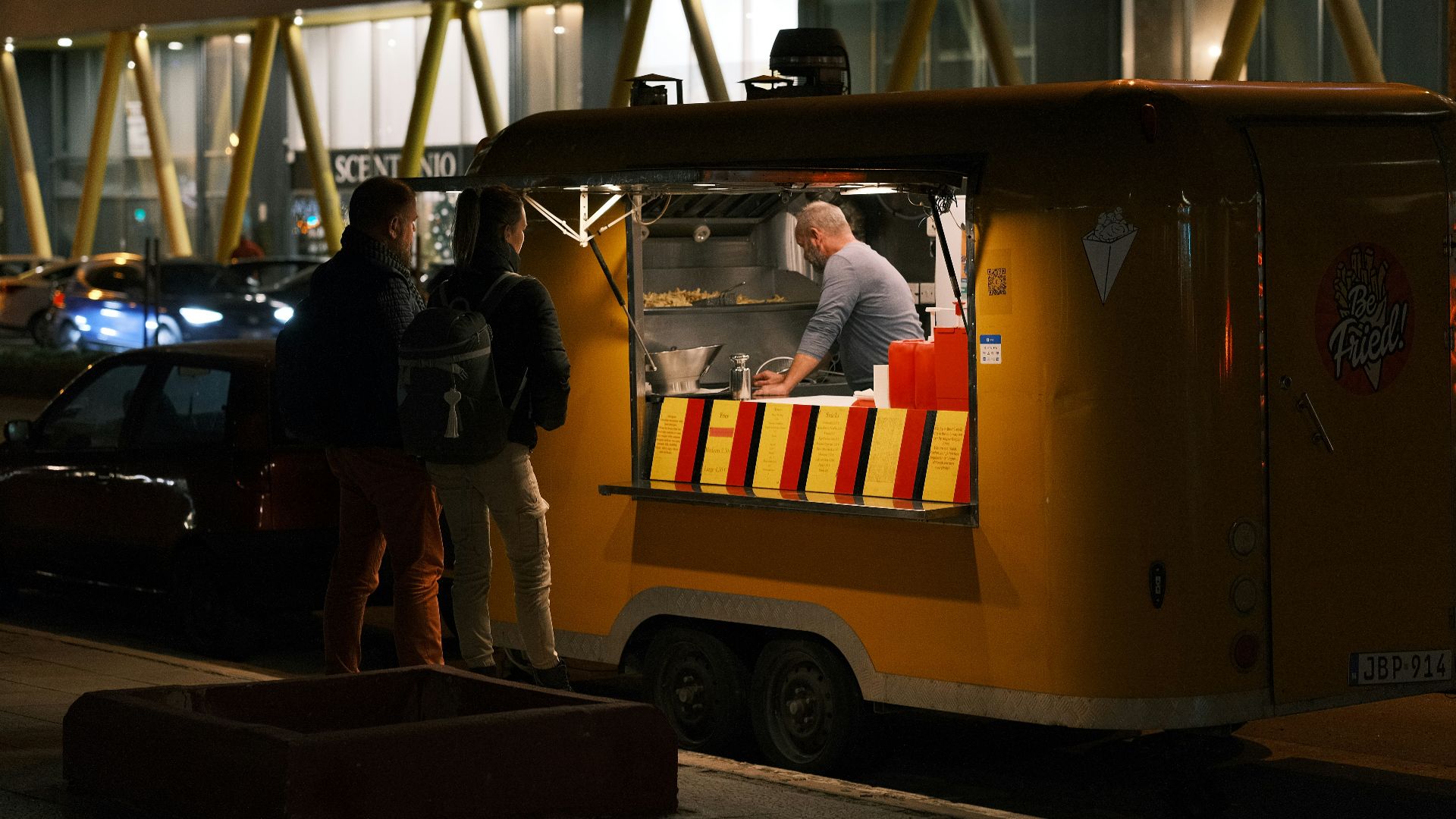a couple of people standing outside of a food truck