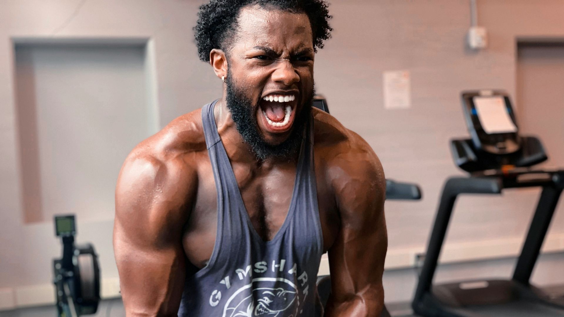 a man with a beard and no shirt on in a gym