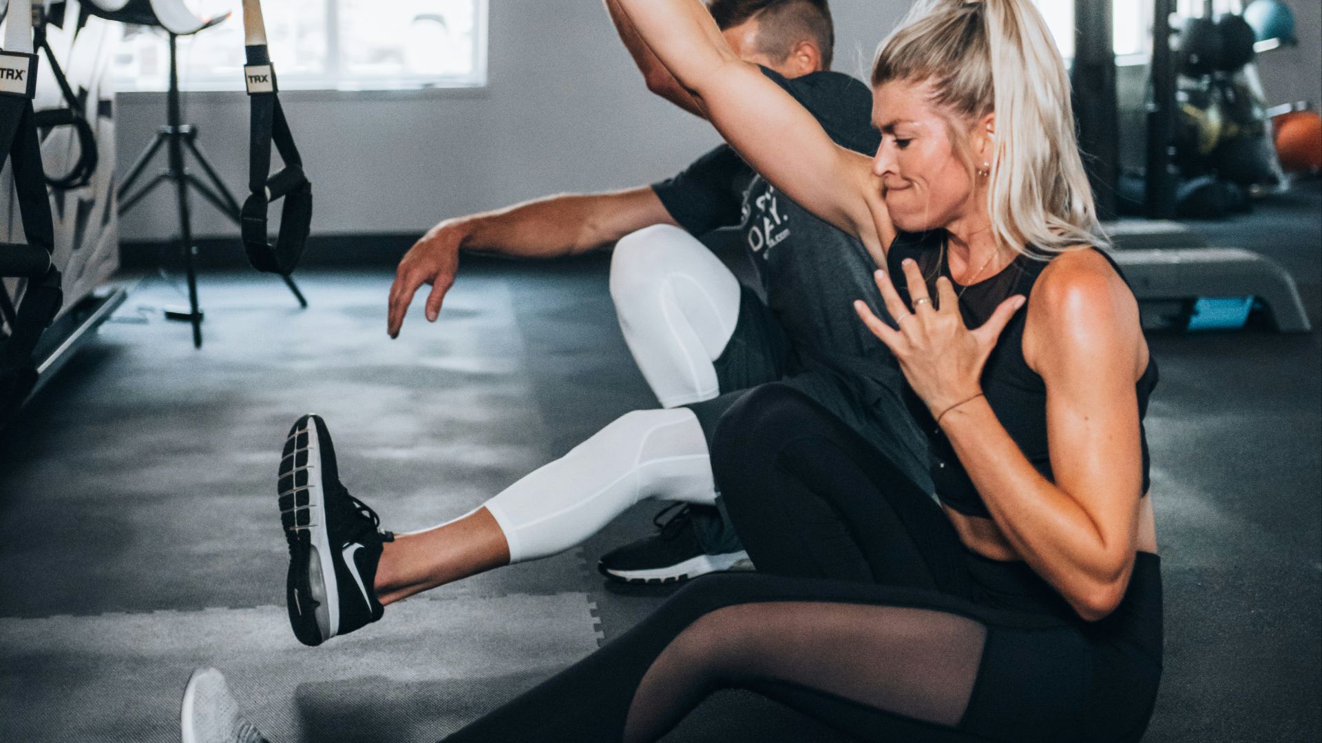 woman in black tank top and white pants sitting on floor
