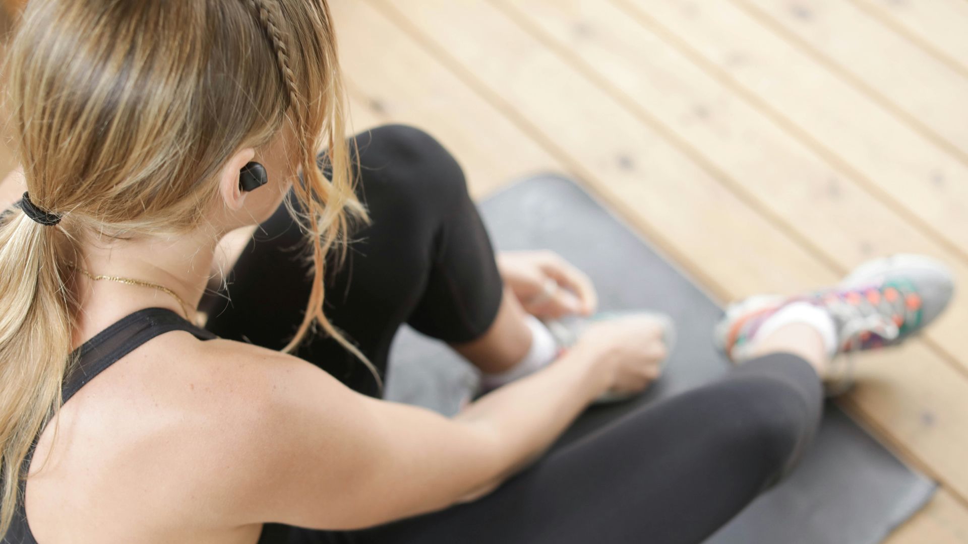 woman in black tank top and black leggings sitting on gray bench