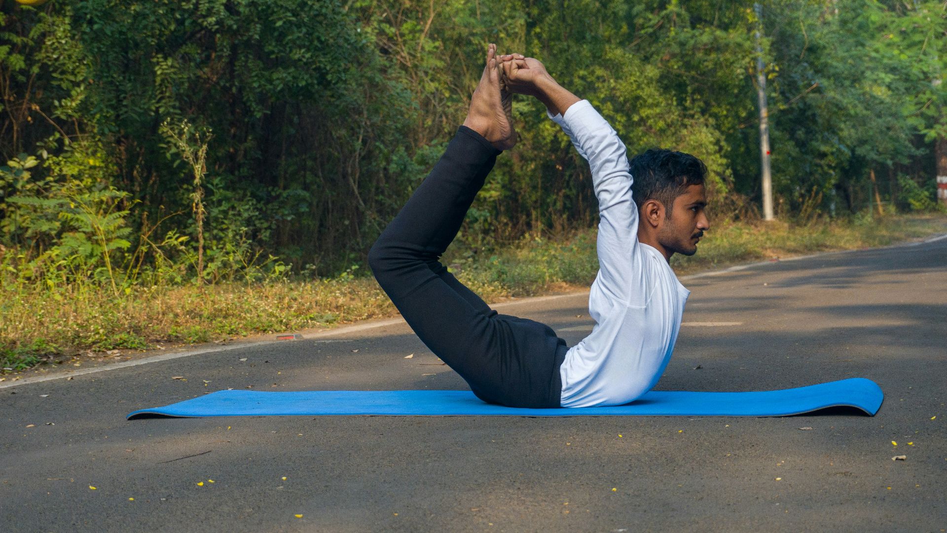 A man doing a yoga pose on a blue mat
