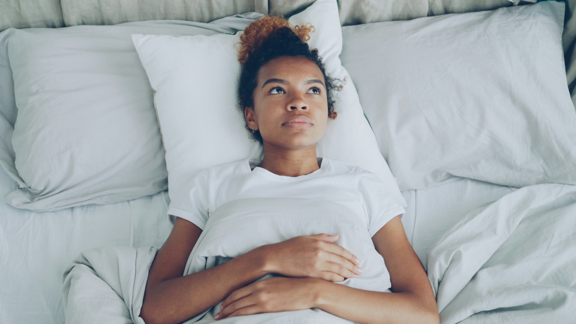 Young woman lying in bed with pillow.