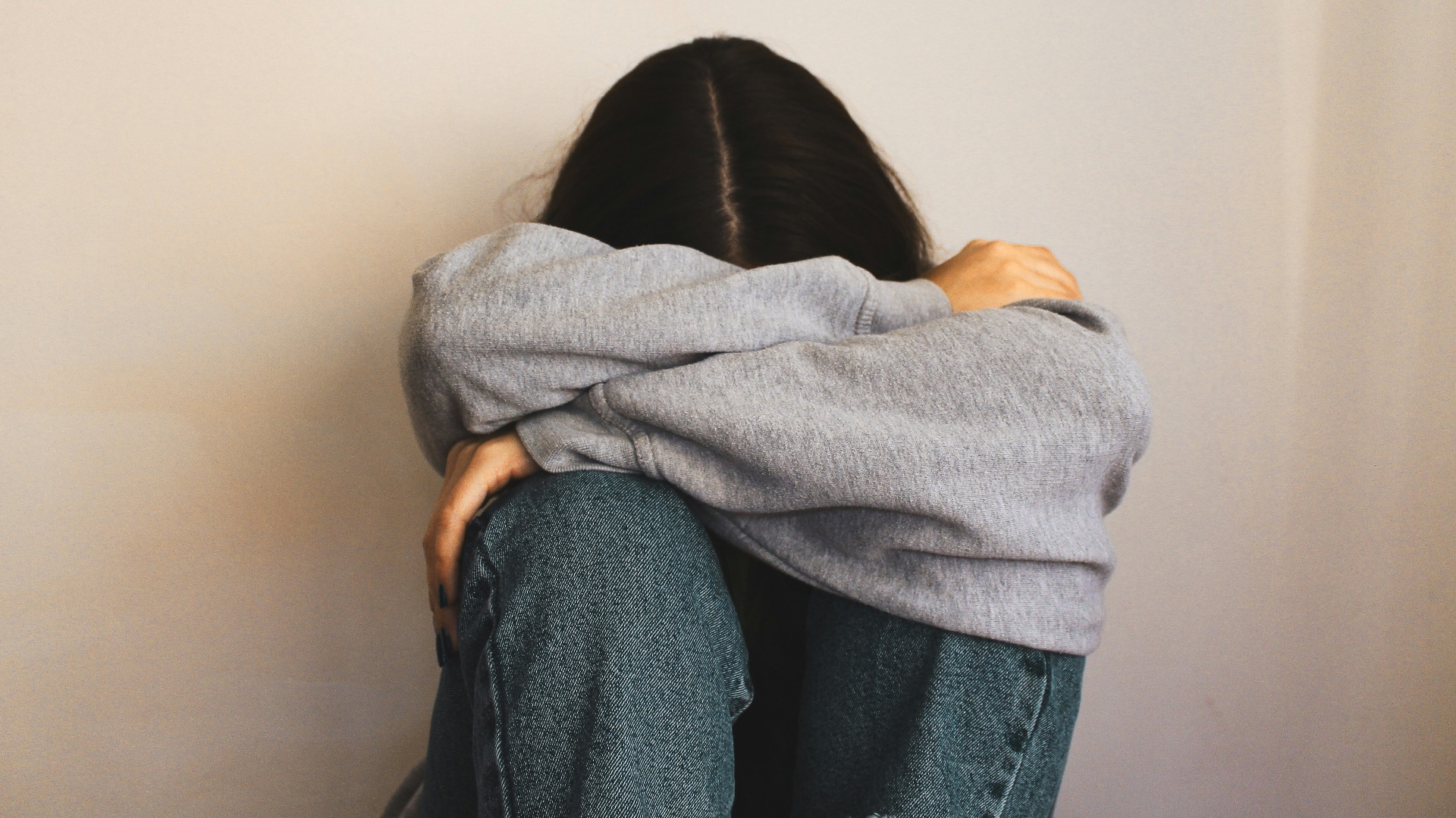 a woman sitting on the floor with her arms wrapped around her head