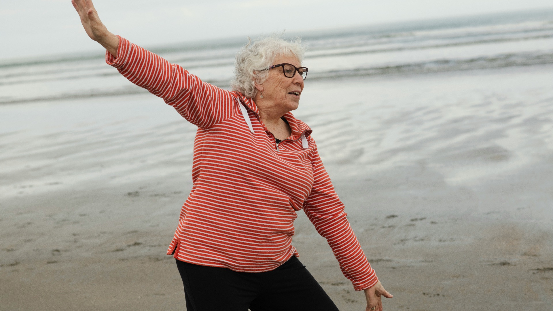 Woman practices tai chi on the beach.
