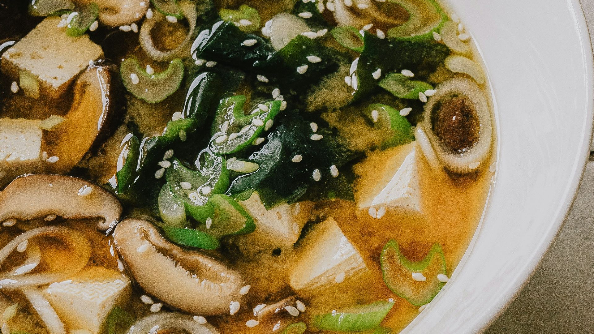 a white bowl filled with soup on top of a tiled floor