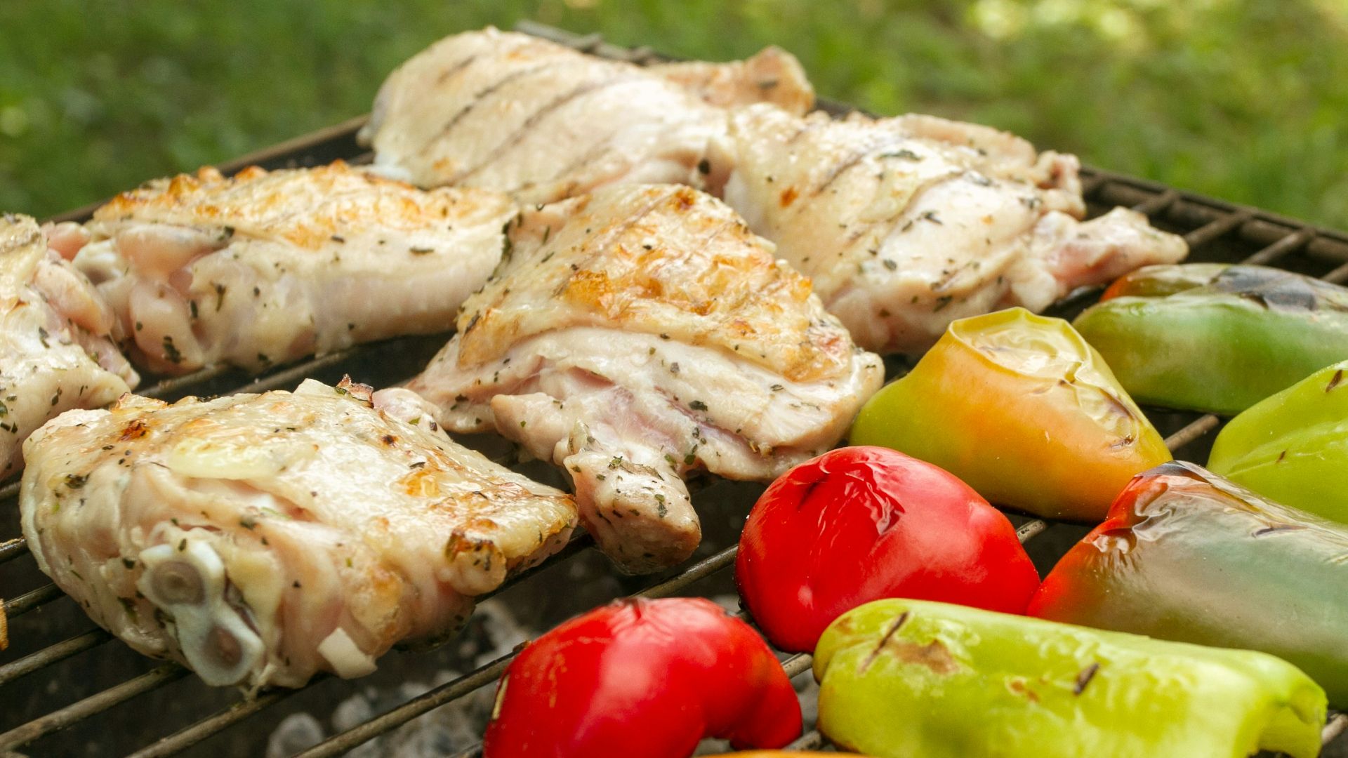 a bbq with chicken, peppers, and peppers on it