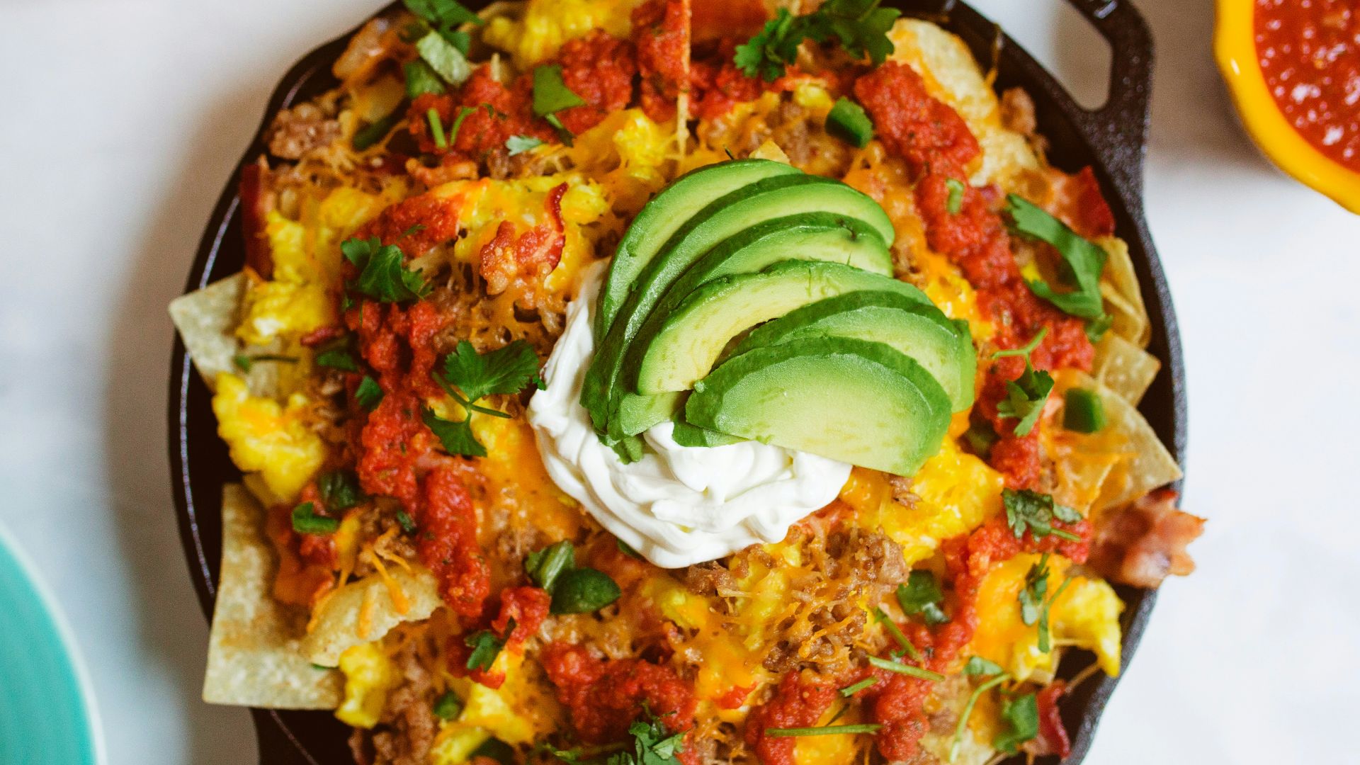 a skillet filled with nachos, salsa, guacamole and