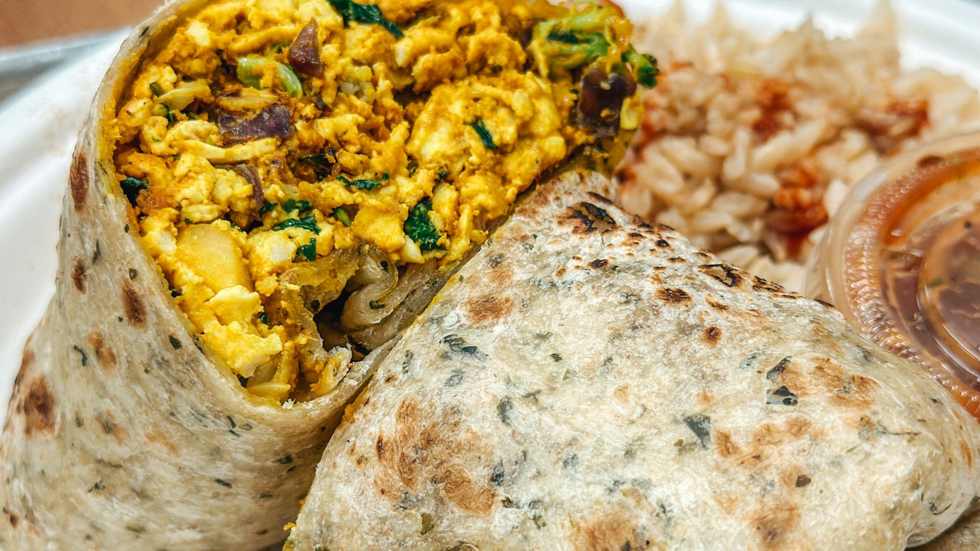 a white plate topped with a burrito and rice