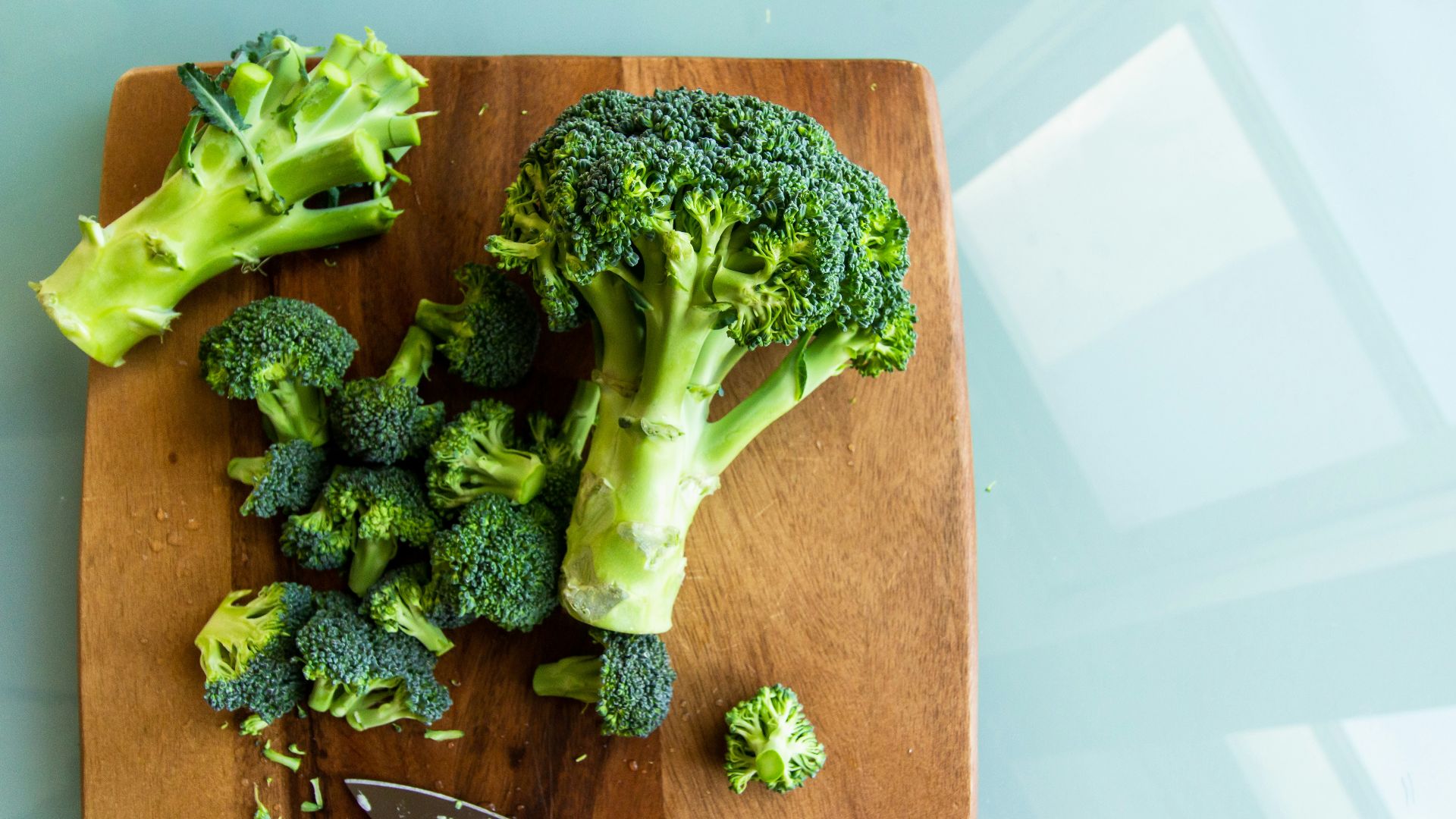 broccoli on brown wooden chopping board