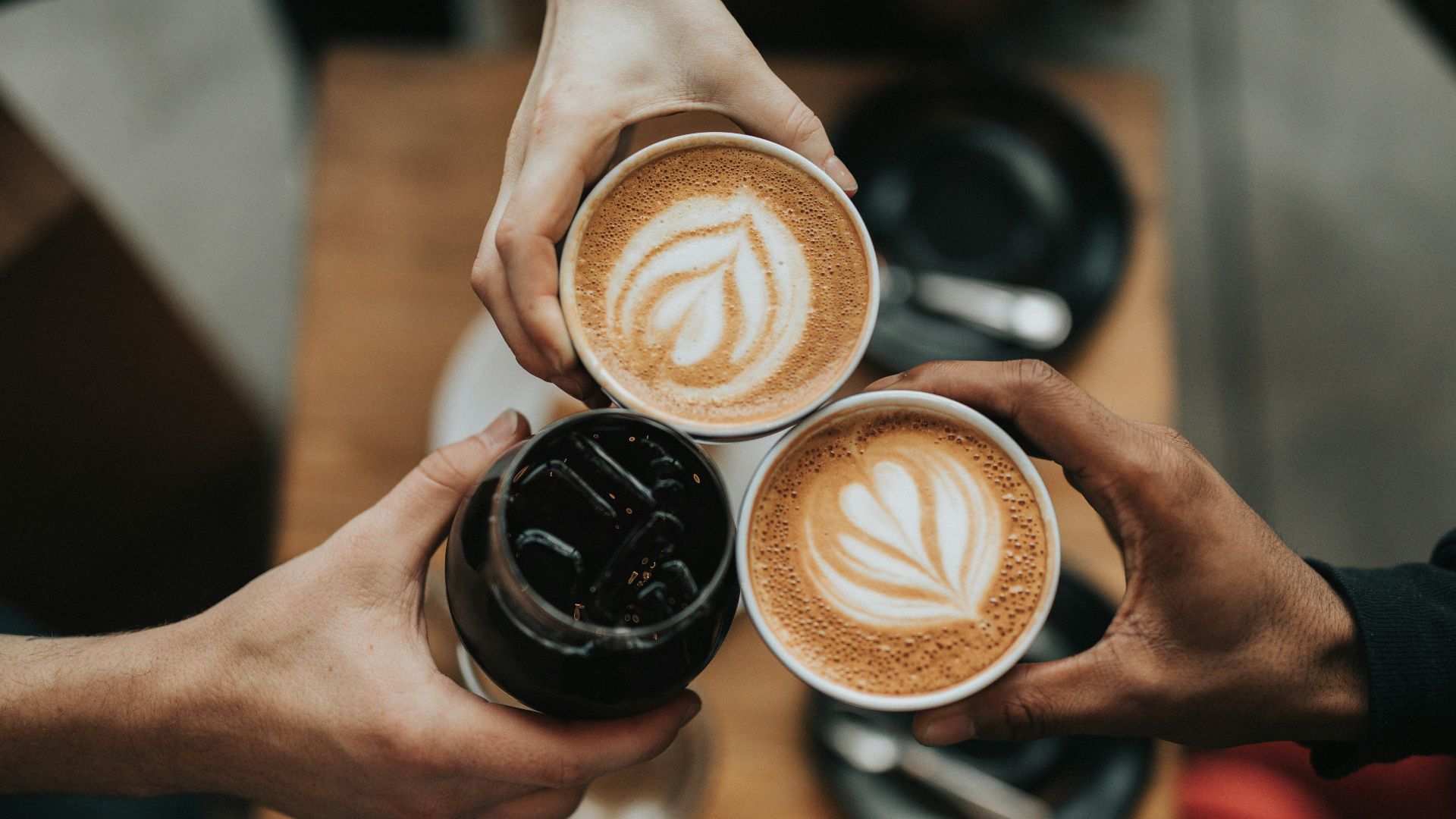 three person holding beverage cups