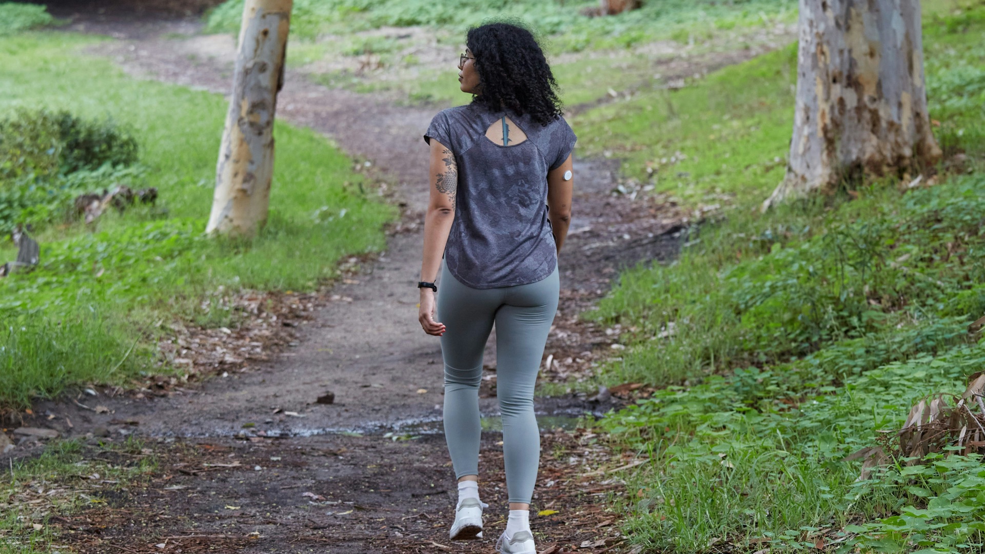 a woman is walking down a path in the woods