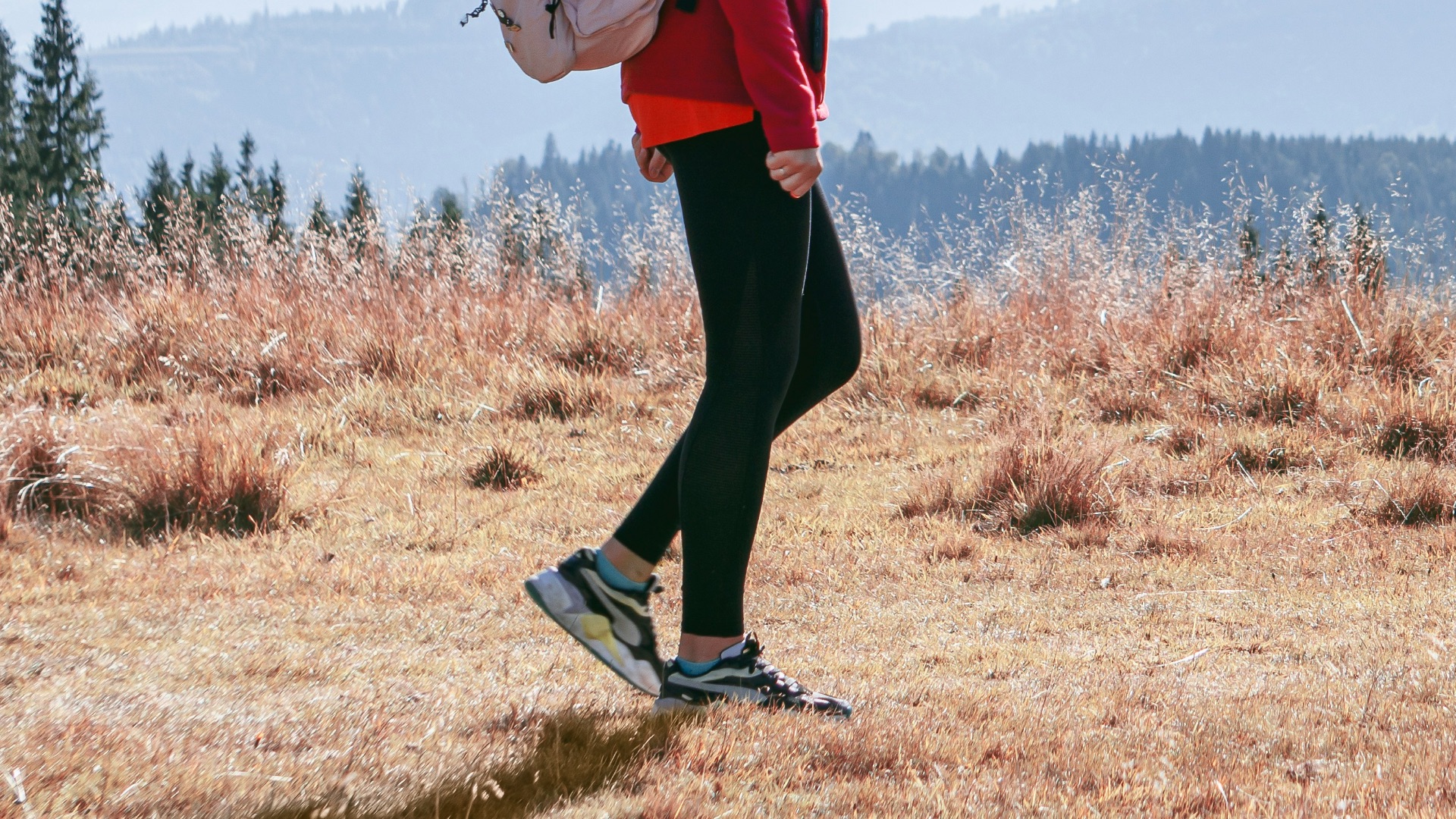 a man with a backpack walking across a dry grass covered field