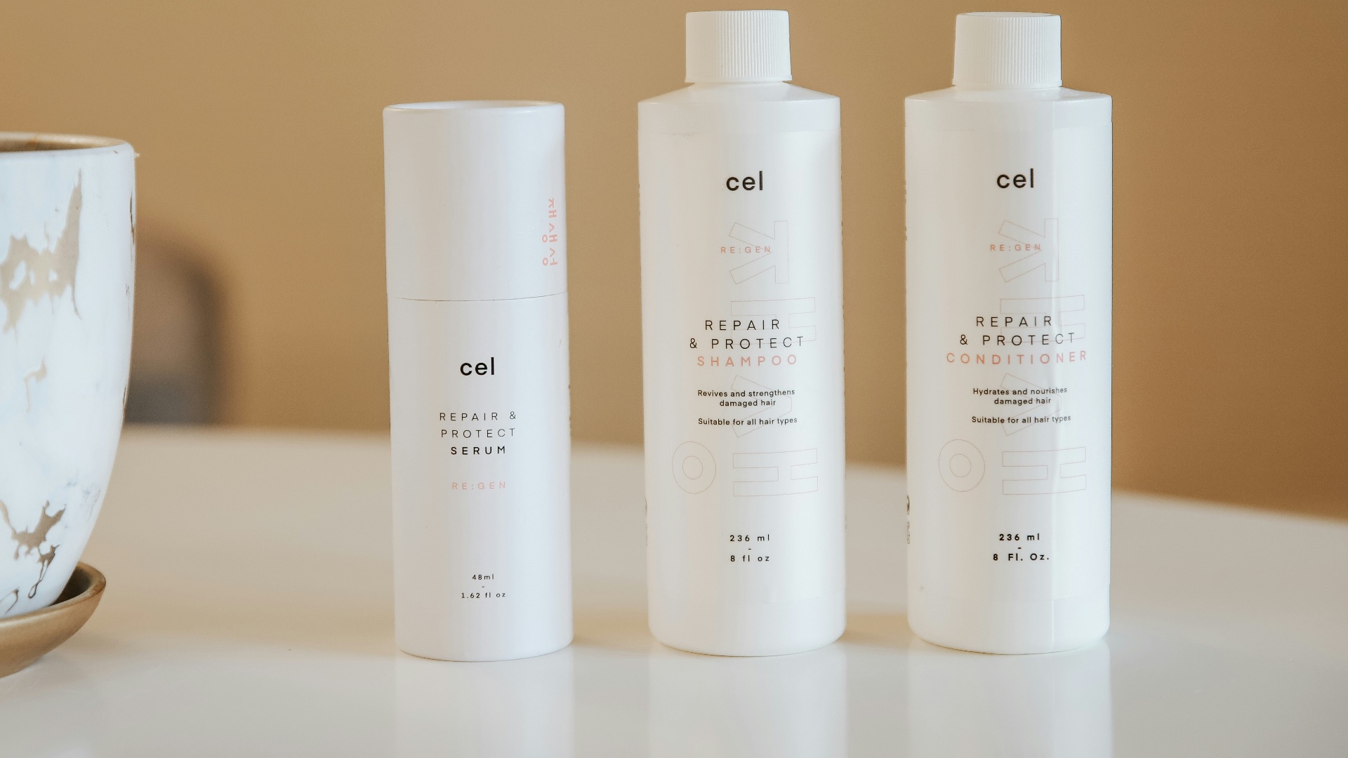 three bottles of lotion sitting on a table next to a potted plant