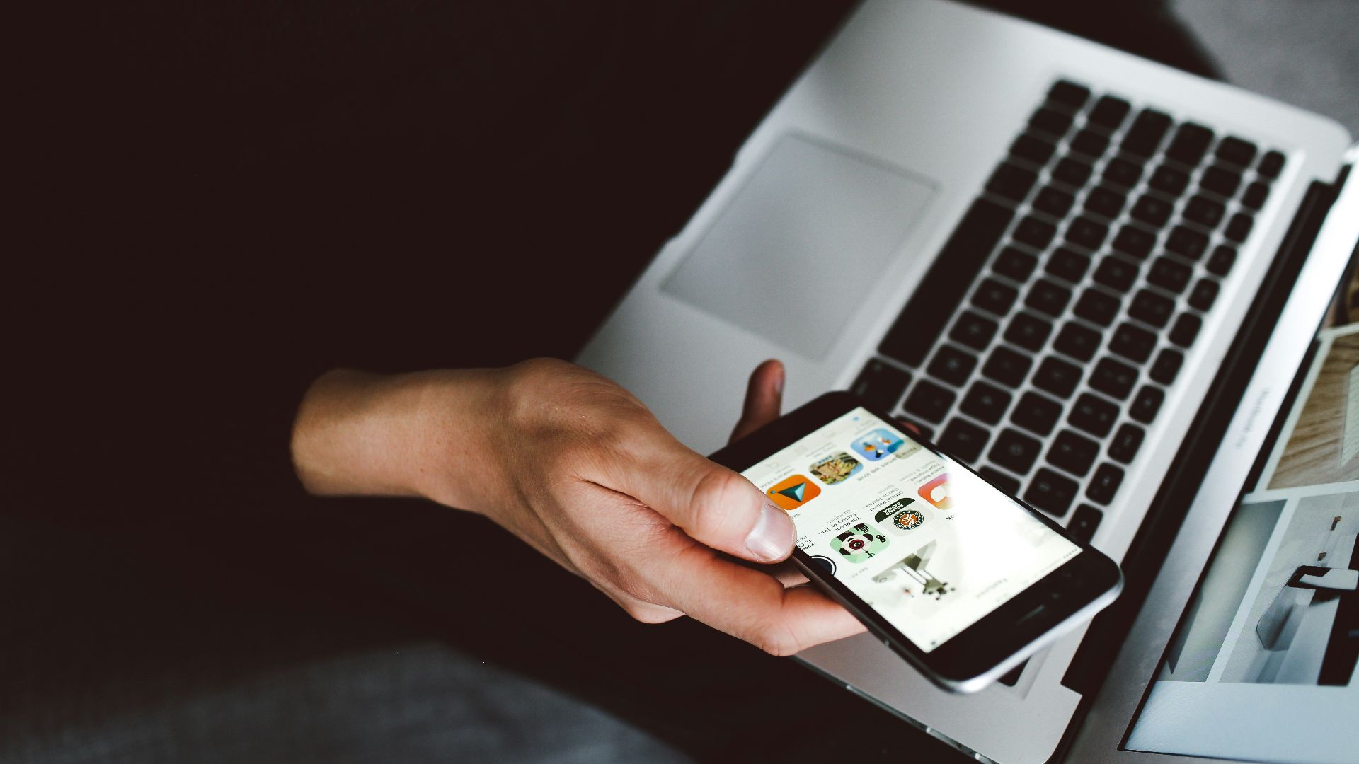 person holding smartphone and laptop