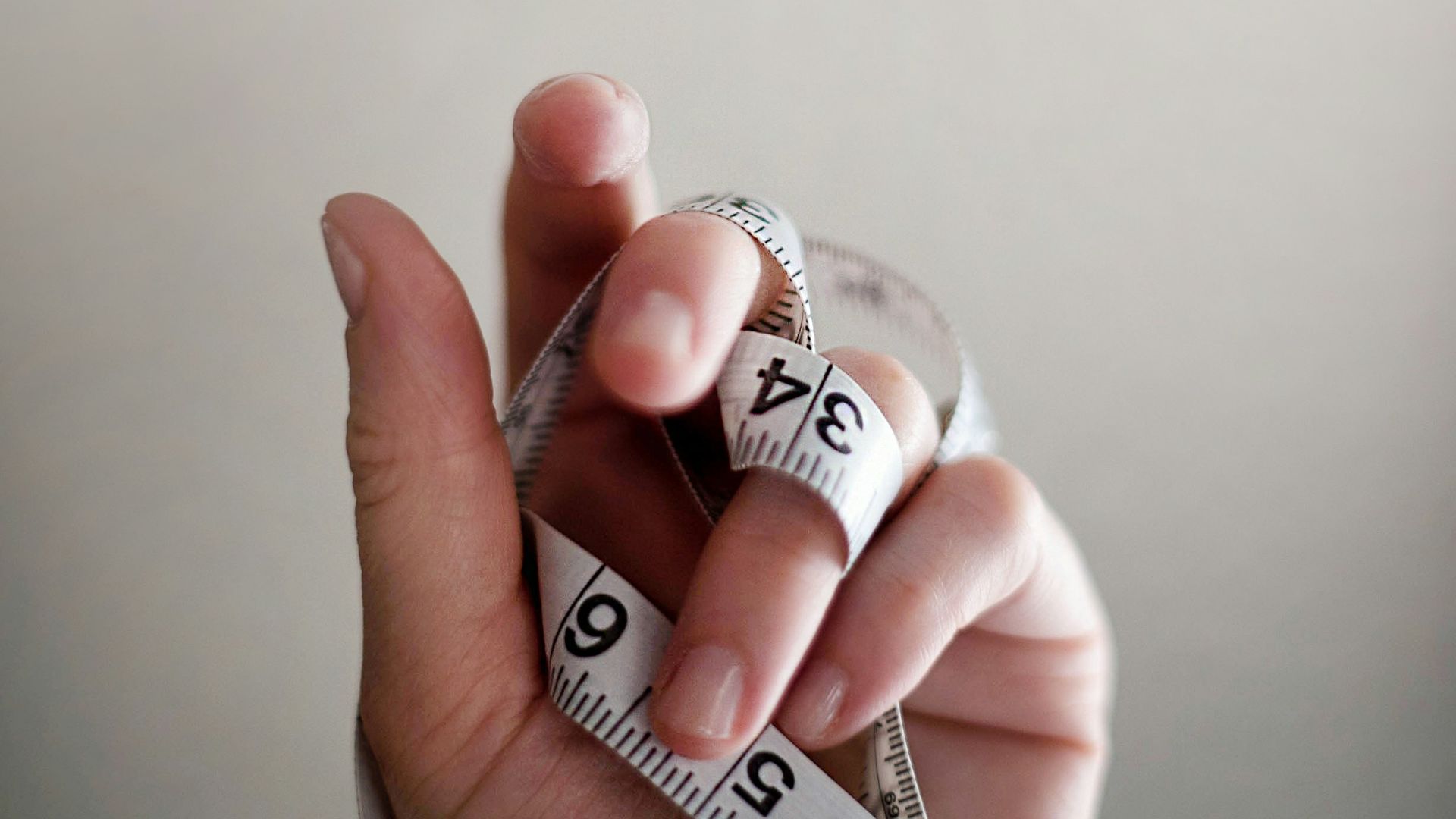 person's left hand wrapped by tape measure