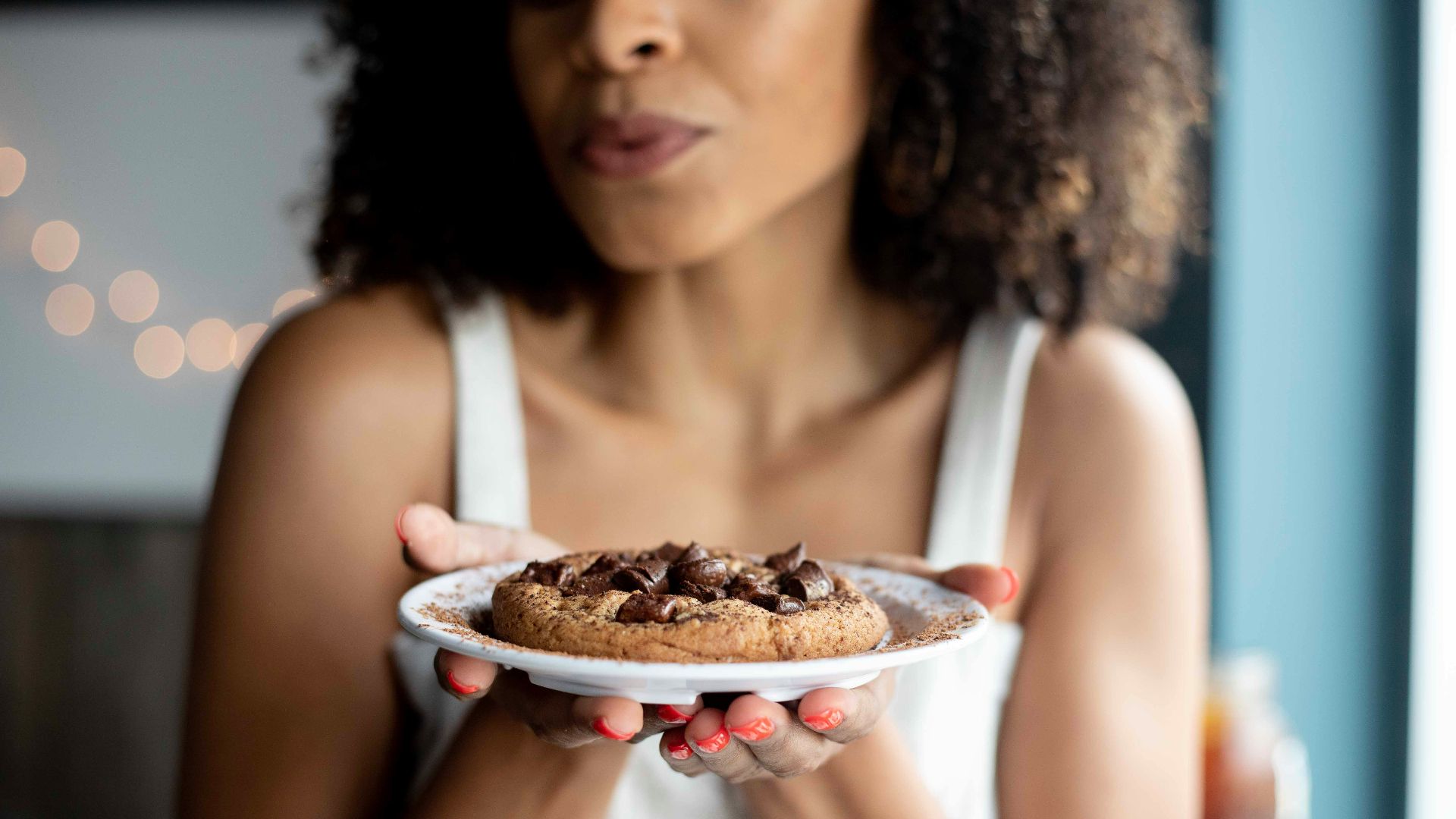 woman holding white ceramic plate with cookies