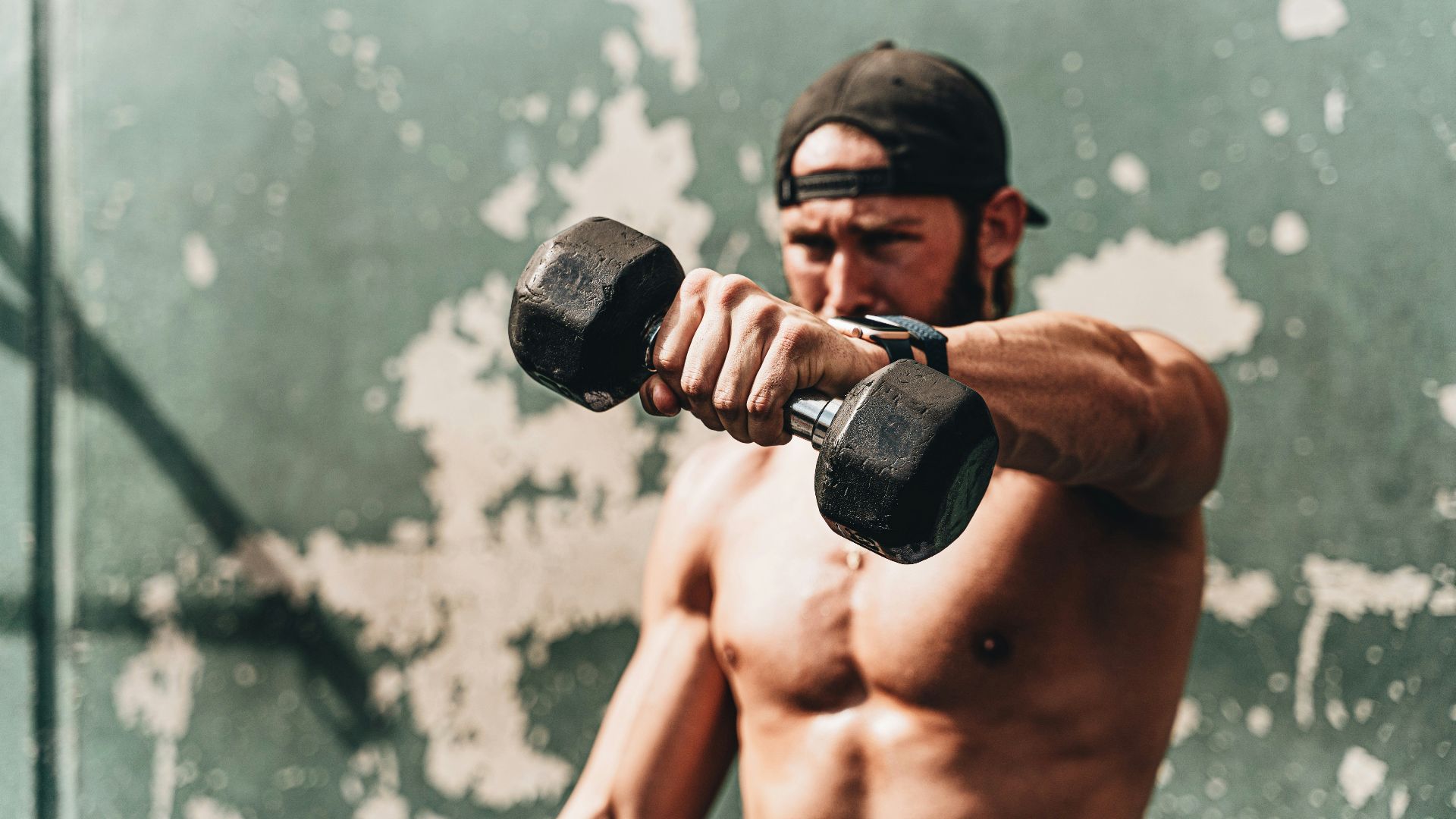 topless man holding black dumbbell