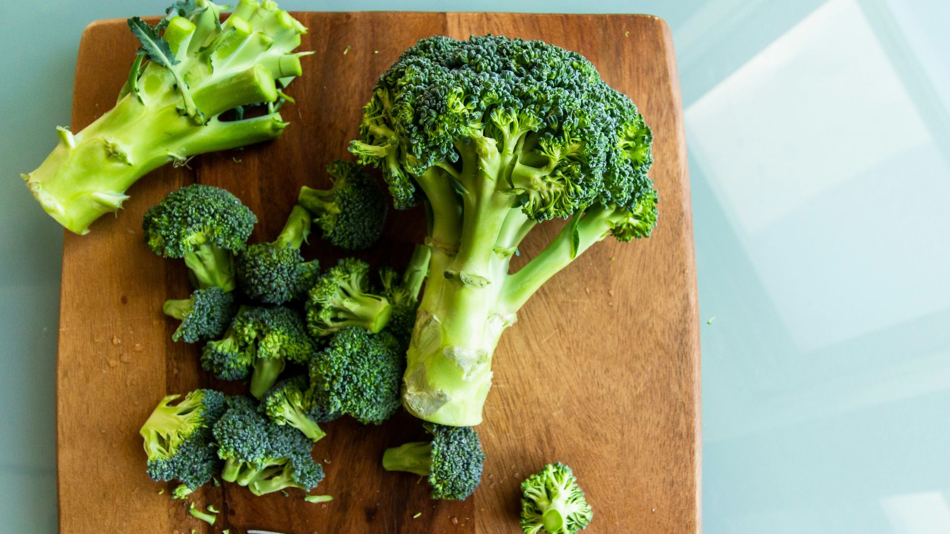 broccoli on brown wooden chopping board