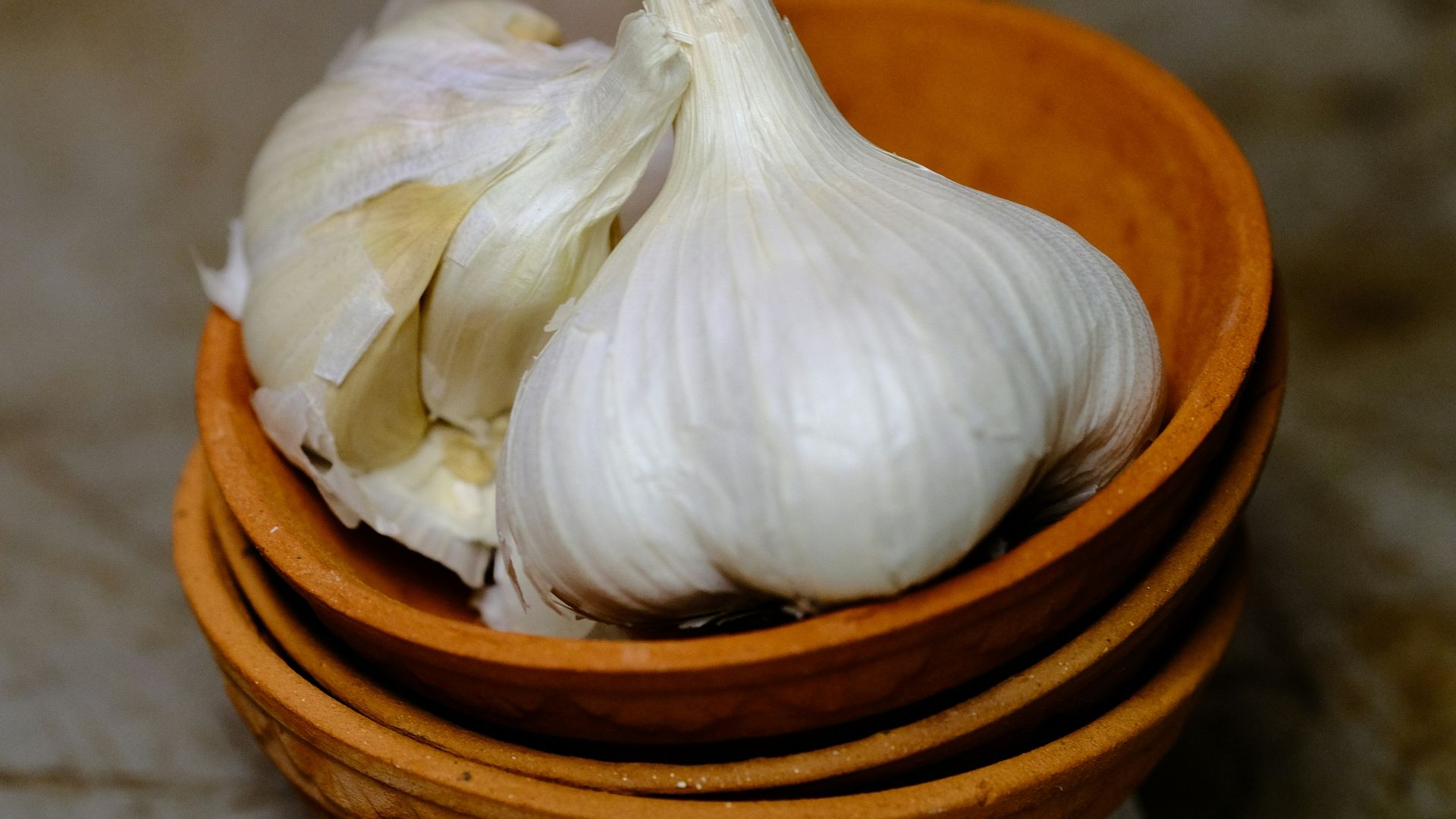 a wooden bowl filled with garlic on top of a counter