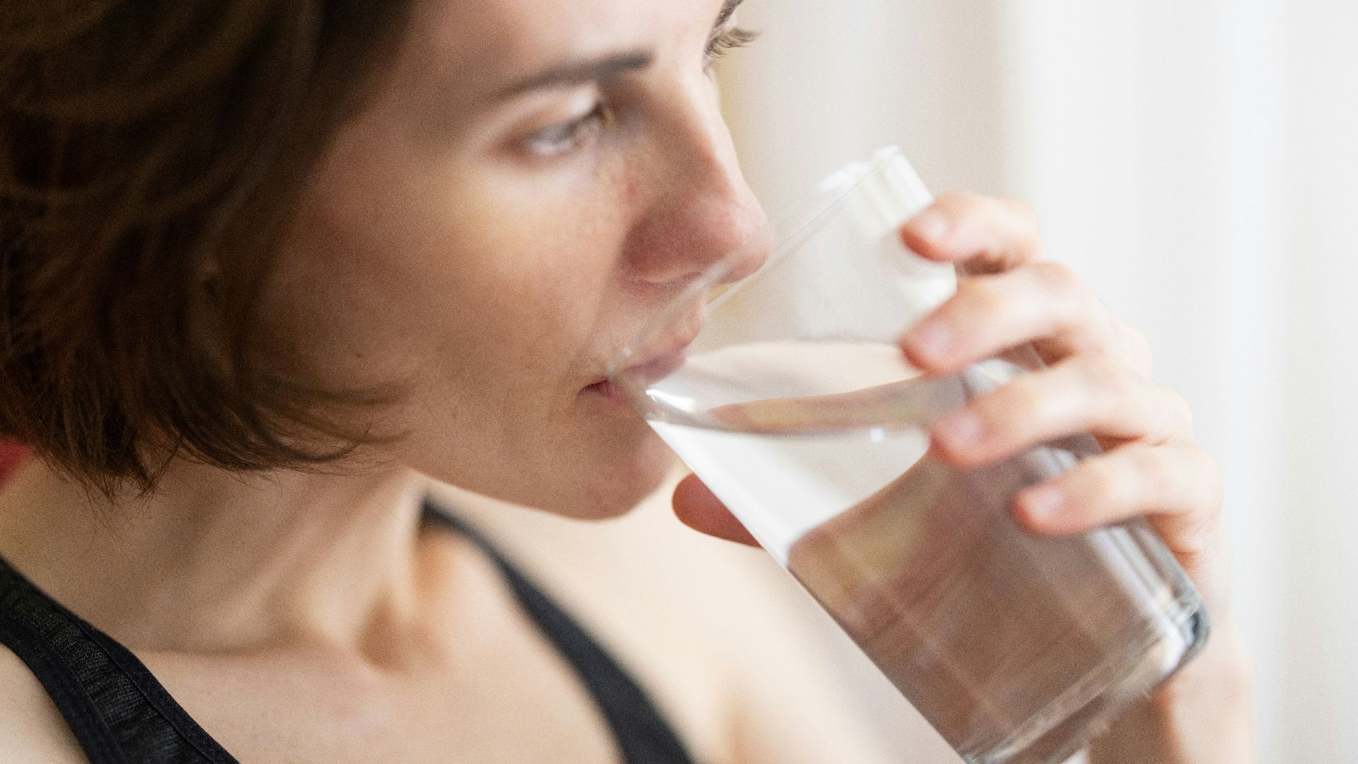 woman in black tank top drinking water