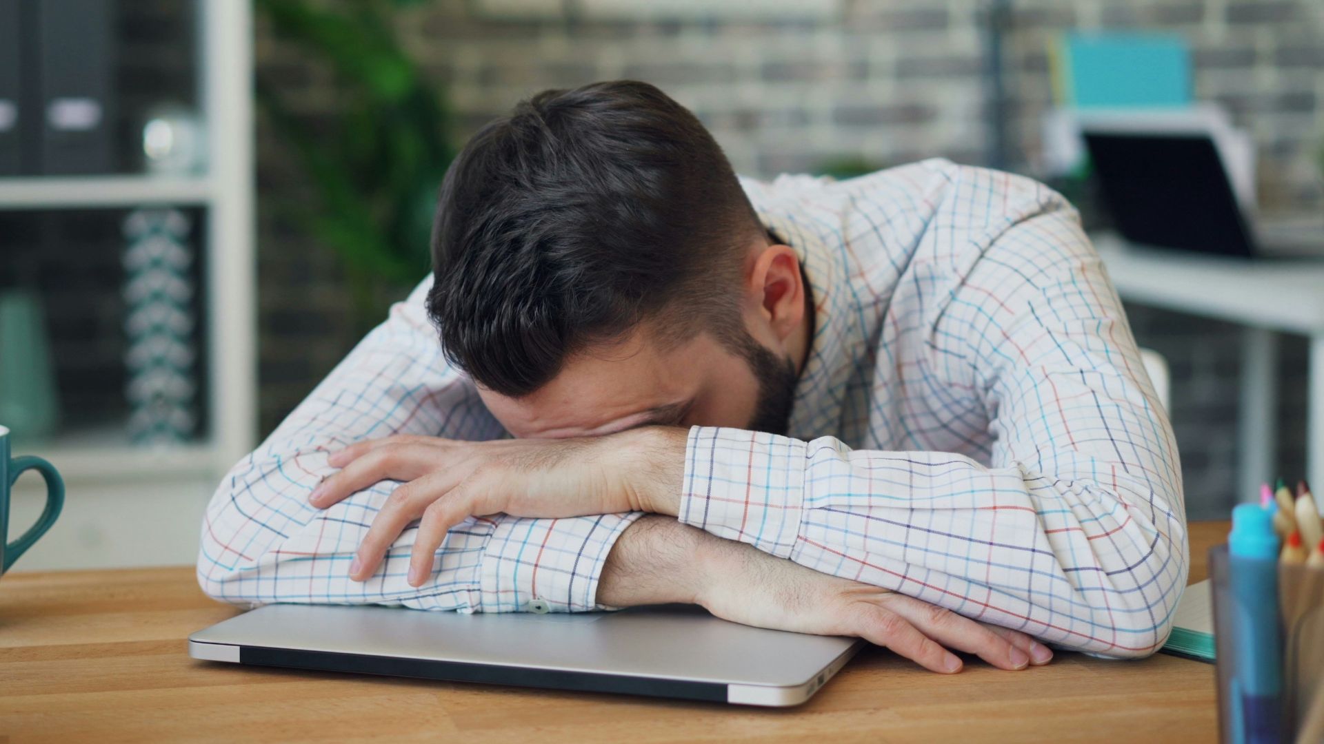 a man sitting at a desk with his head in his hands