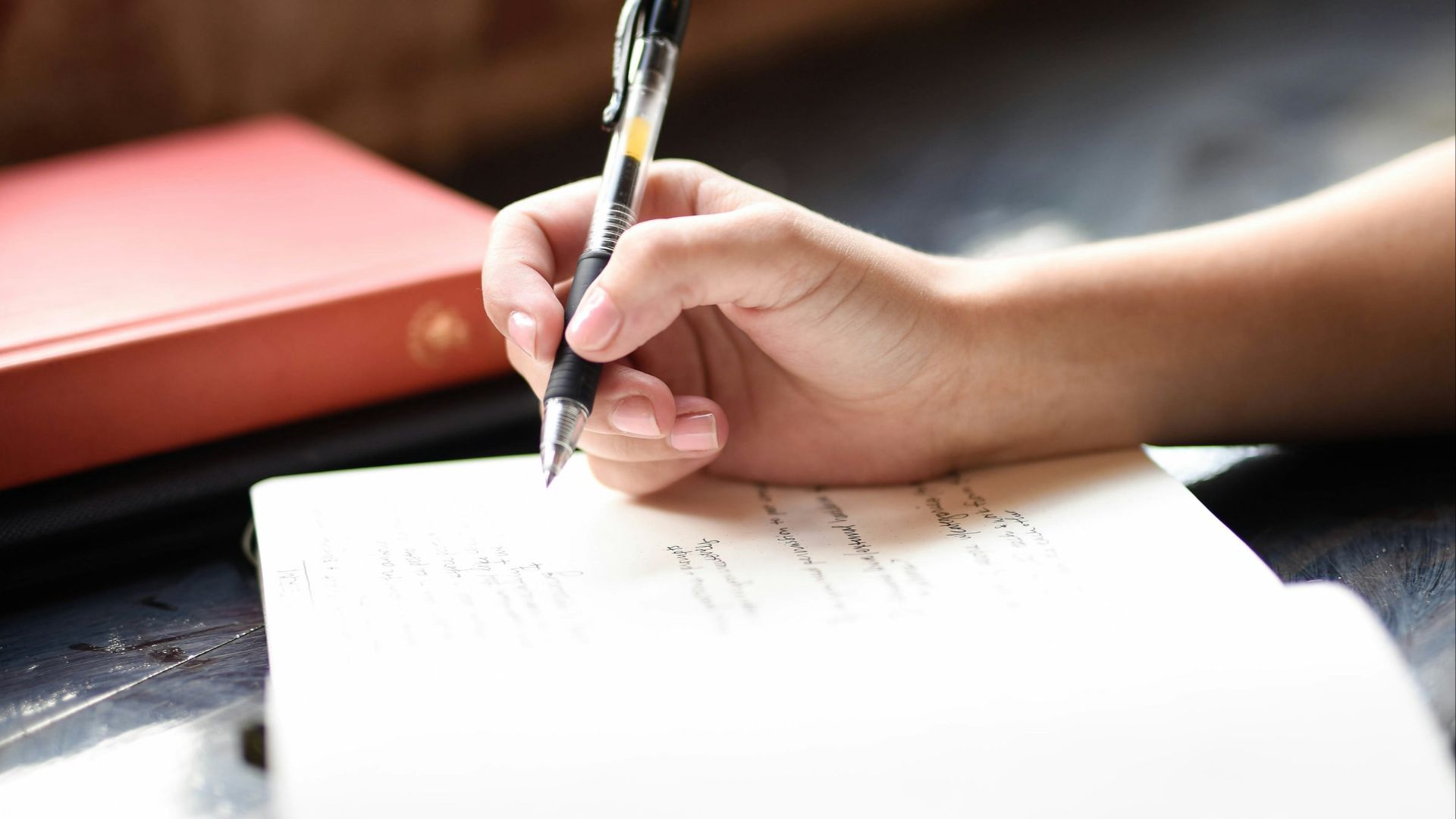 a person writing on a piece of paper with a pen