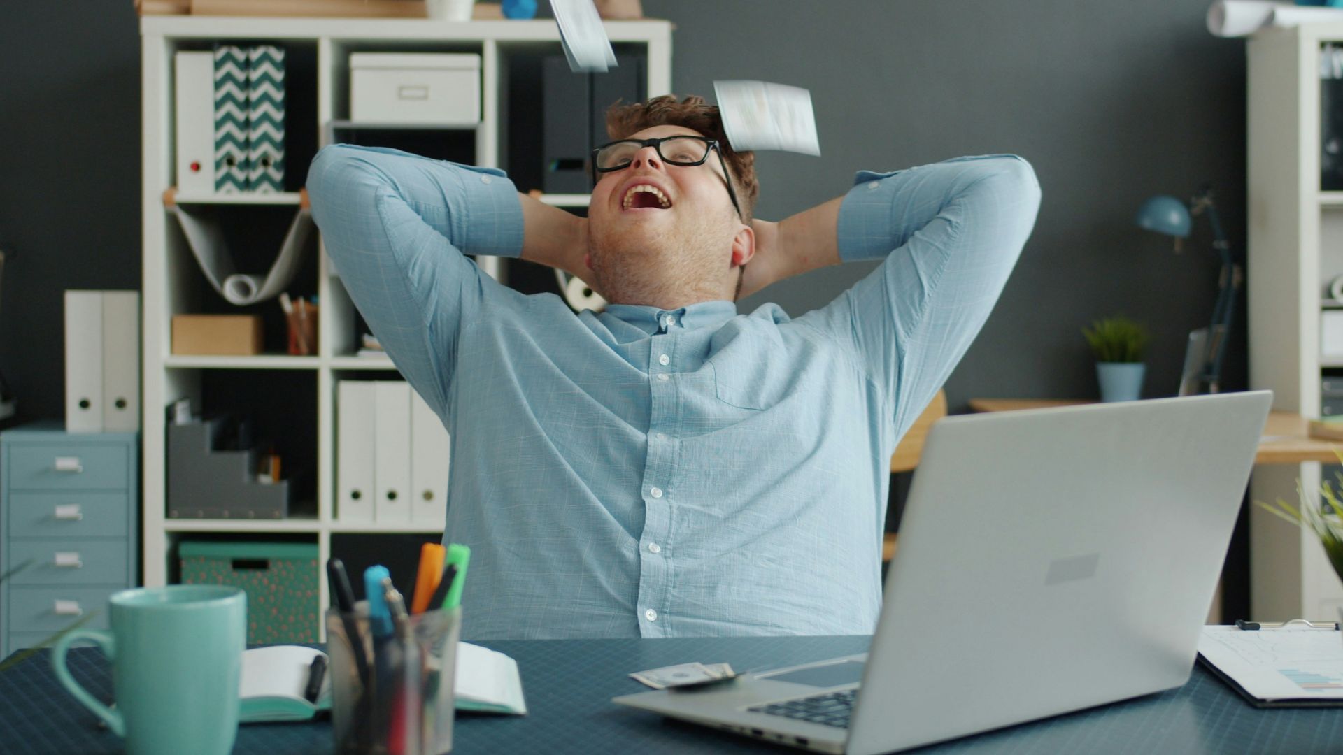 Man celebrating success by throwing papers in office