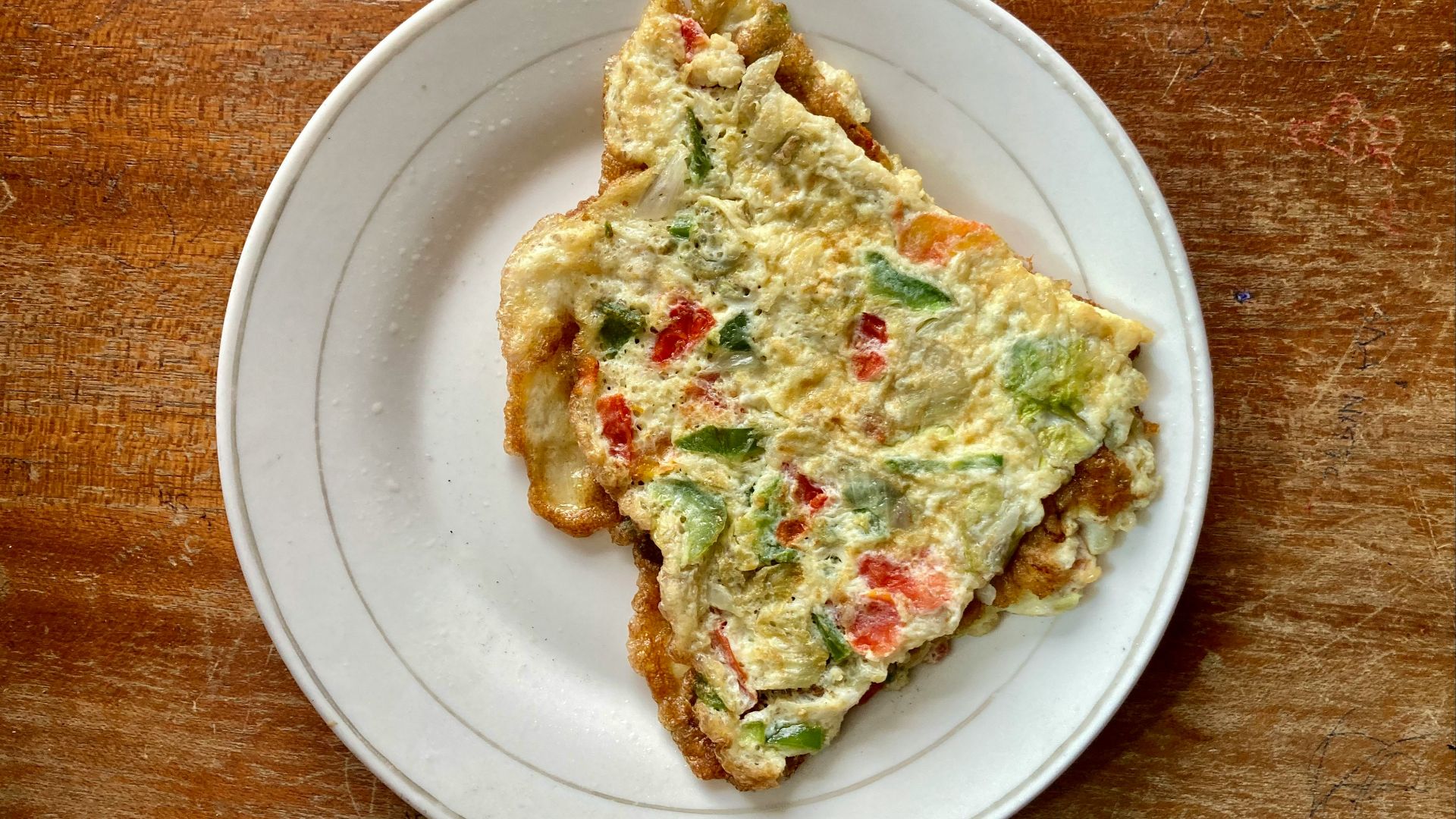 a slice of quiche on a white plate on a wooden table