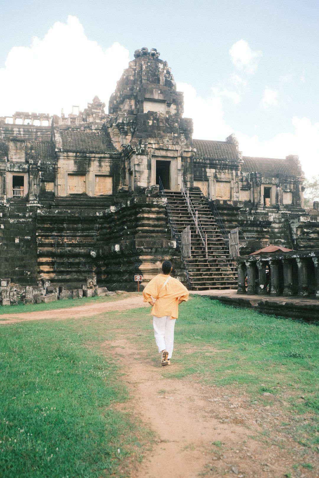 A person walking down a dirt path in front of a building