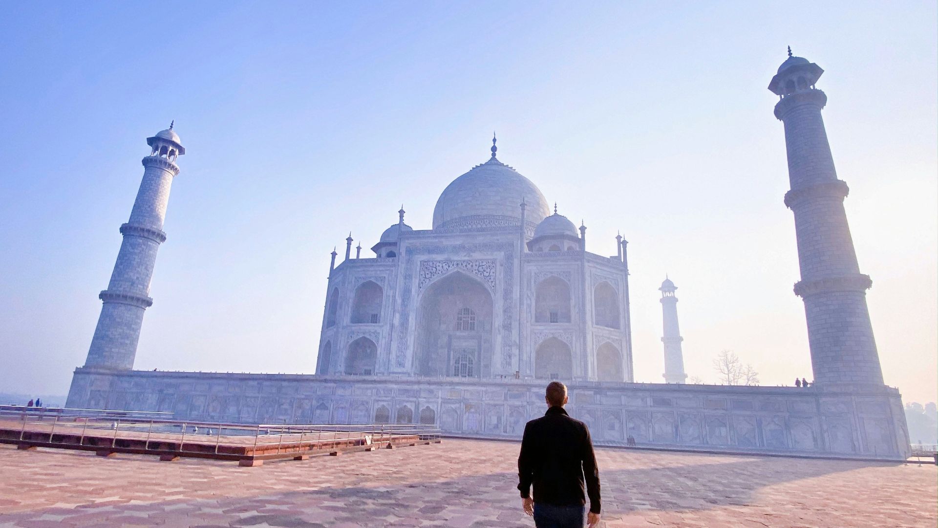 man in black jacket standing near mosque during daytime
