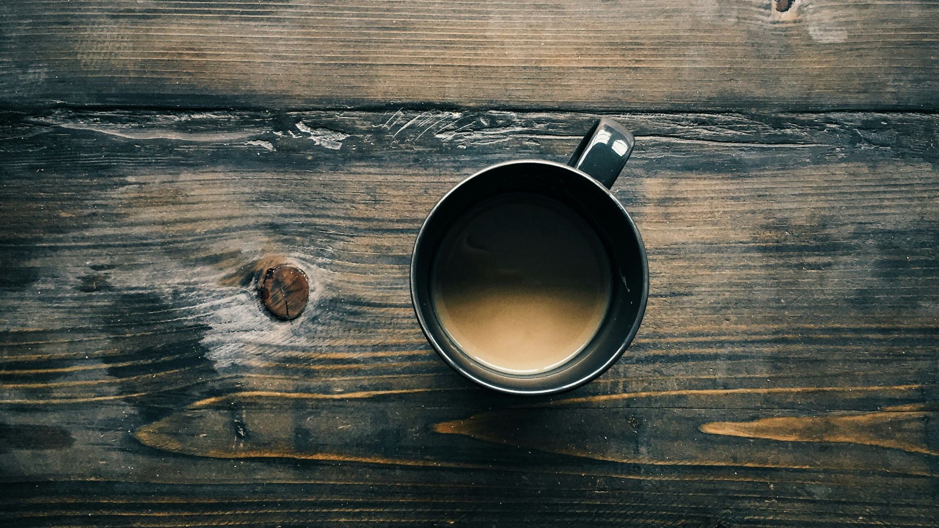 gray cup with brown liquid inside on top of table