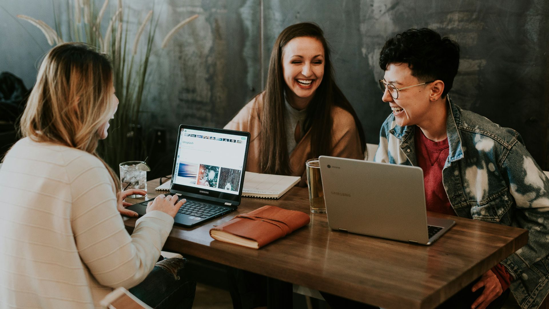 three people sitting in front of table laughing together