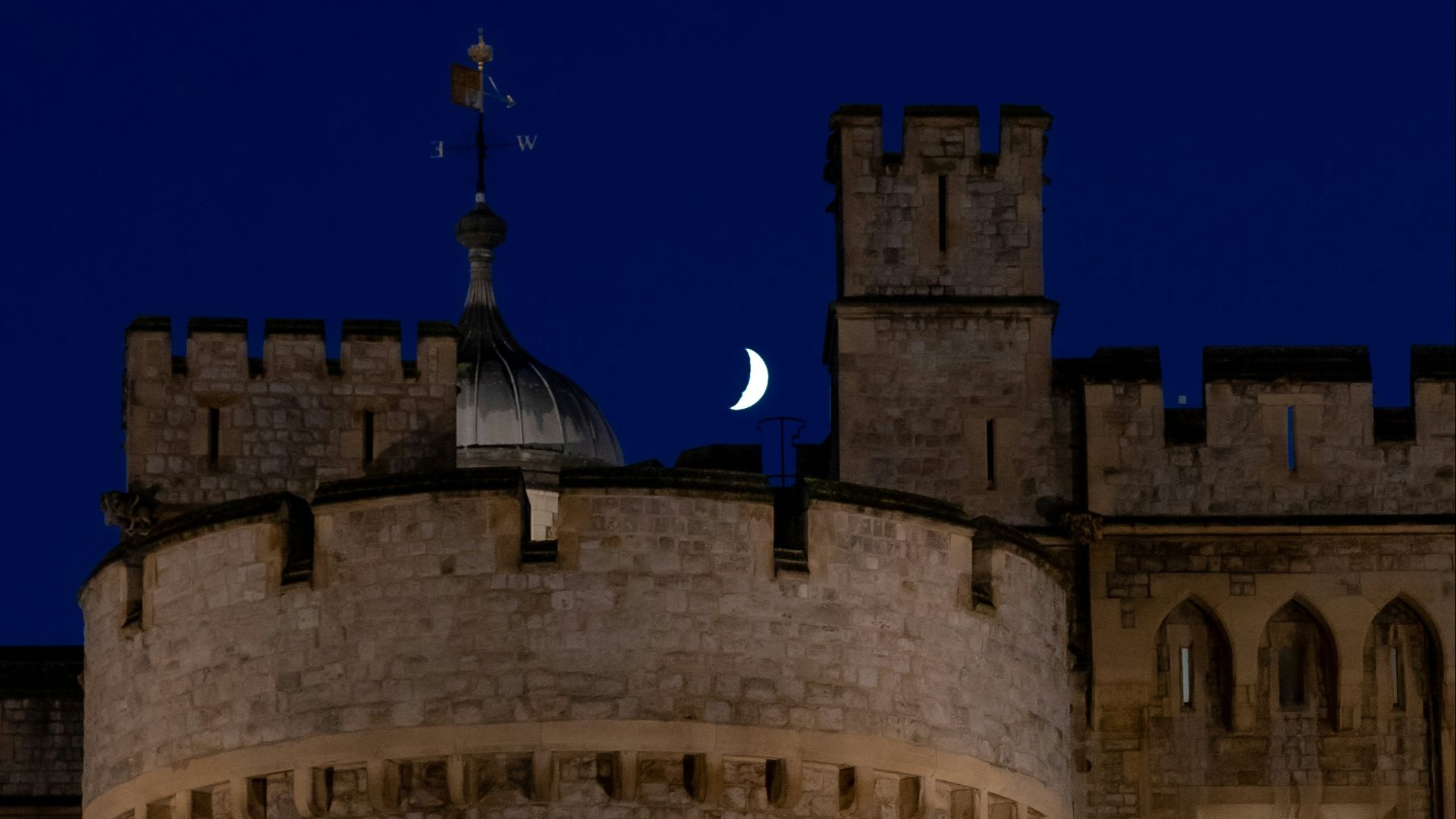 a castle with a clock tower and a moon in the sky