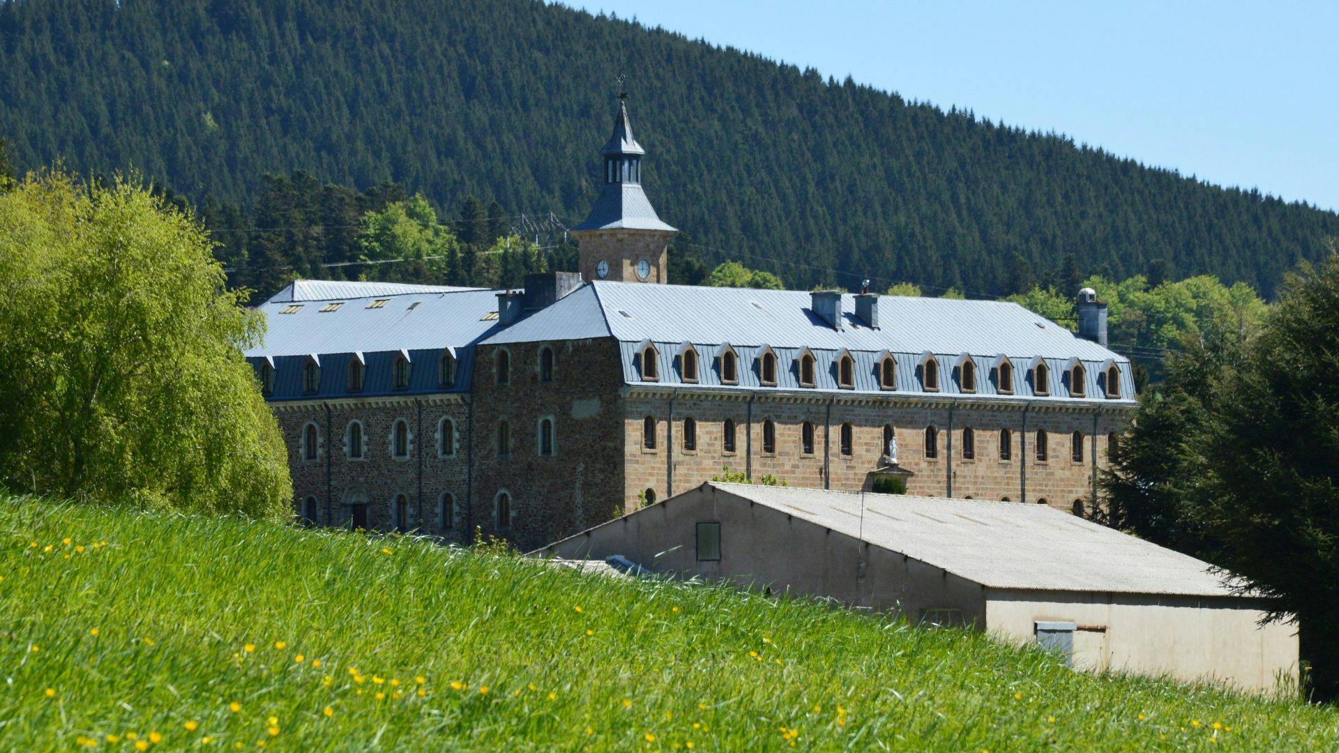 A building sits amongst a green, grassy field.