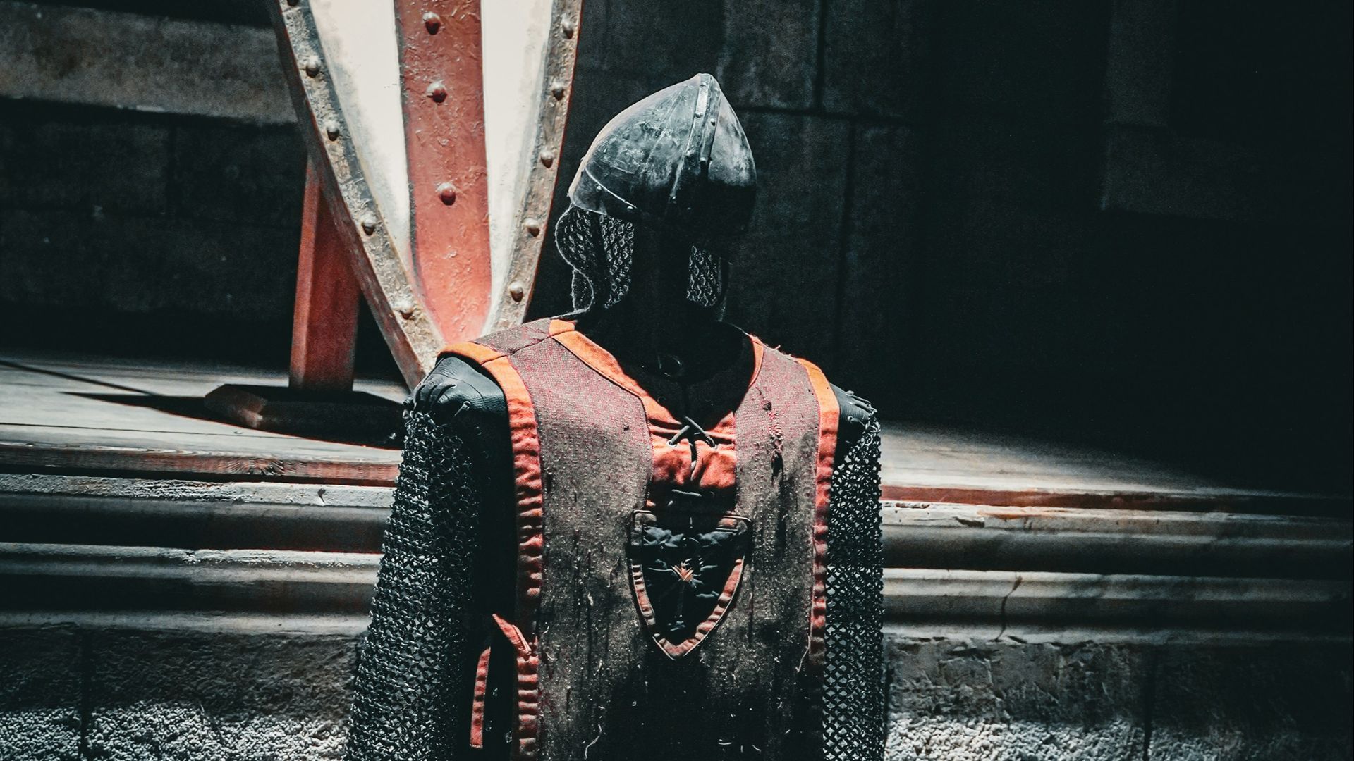 A knight is standing in front of a large shield