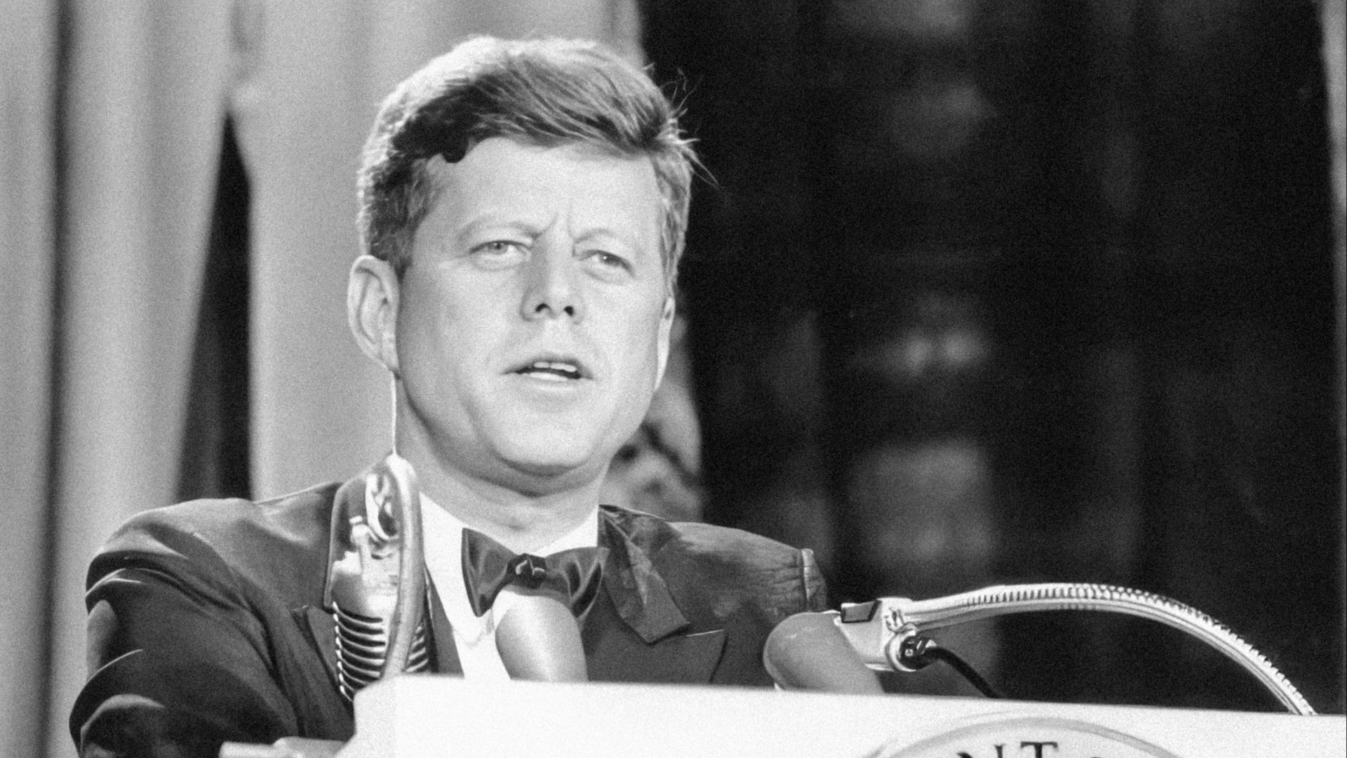 a man in a suit and tie standing at a podium