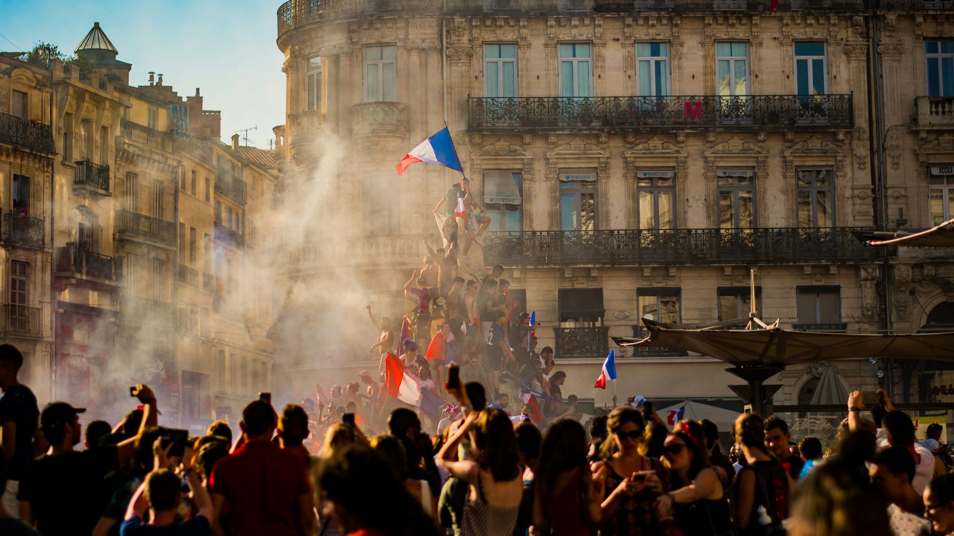 people waving flag of France near building