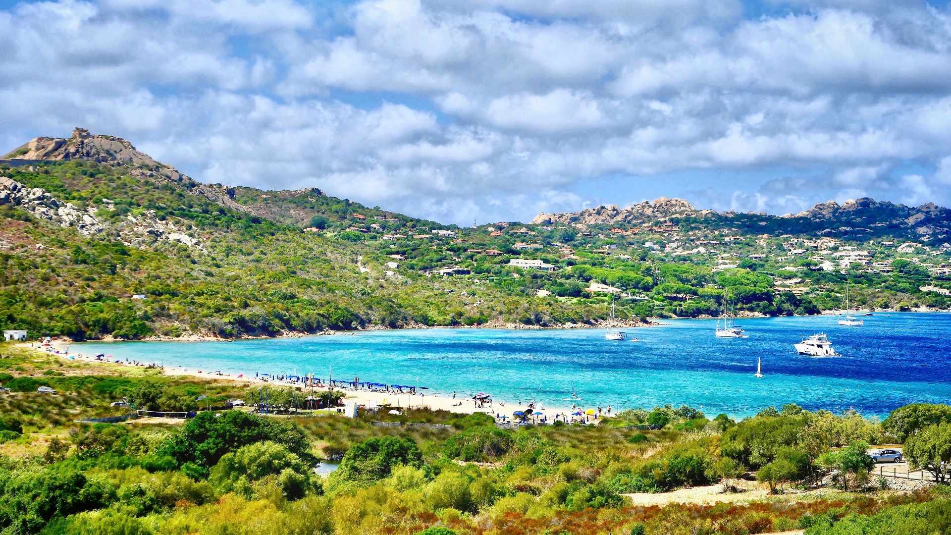 green grass field near body of water under white clouds during daytime