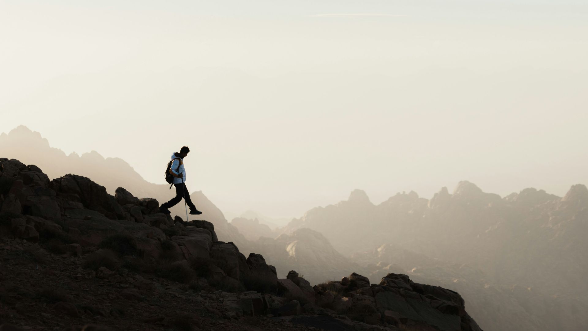 a man running up a mountain with a sky background