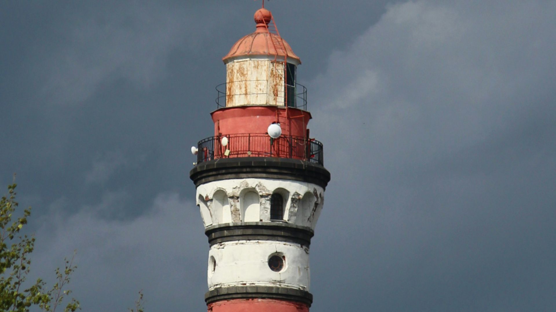 a red and white lighthouse with trees in the foreground