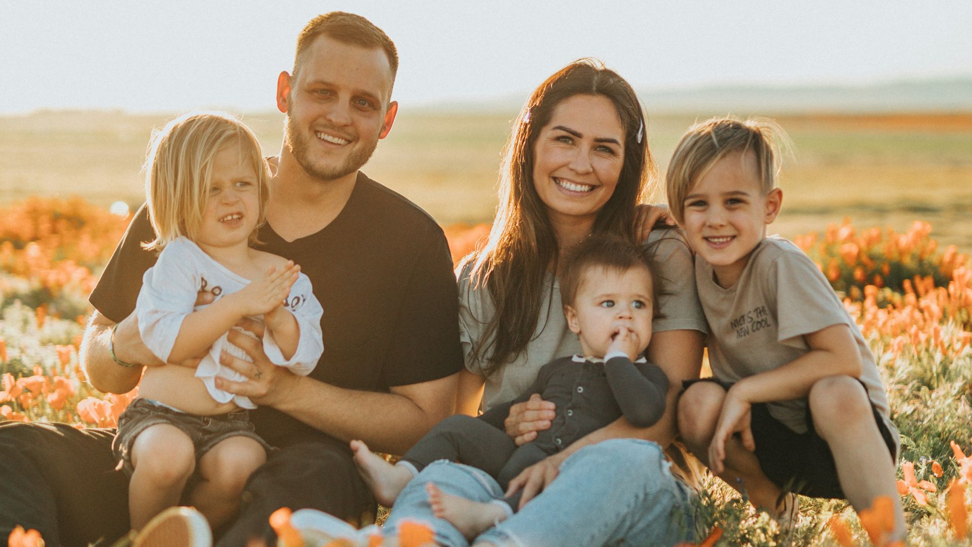3 women and 2 men sitting on green grass field during daytime