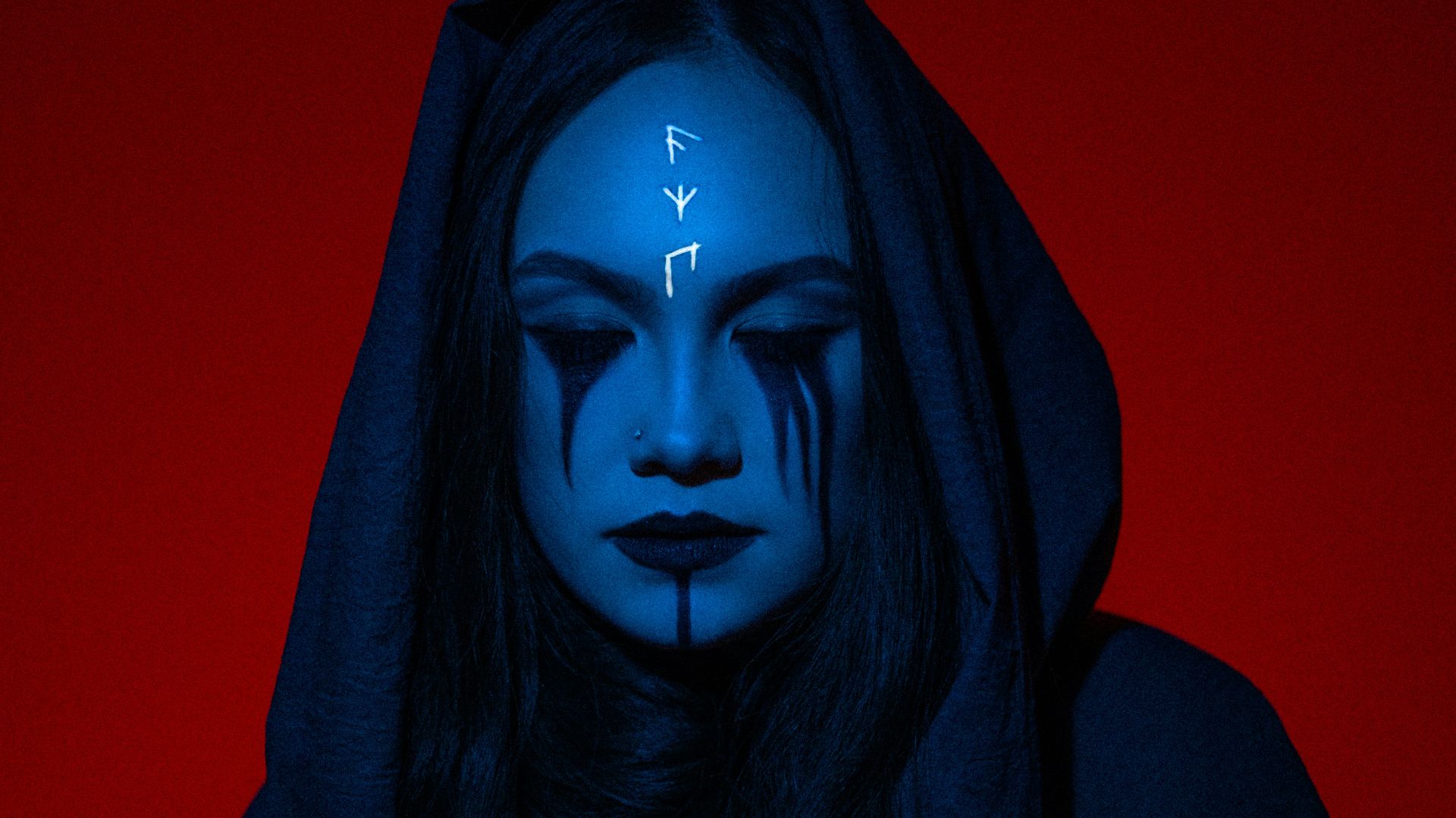 a woman with blue makeup and a hoodie with arrows painted on her face